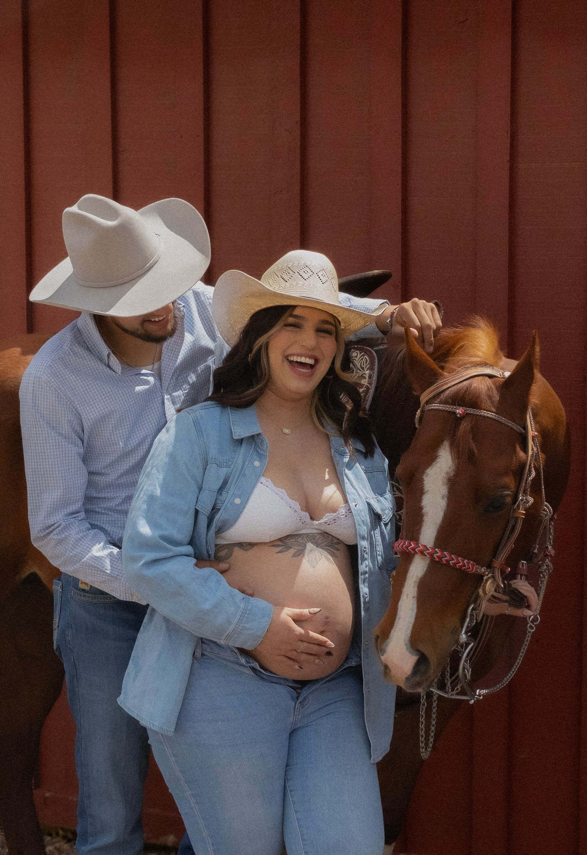 A man and a pregnant woman are standing next to a horse.