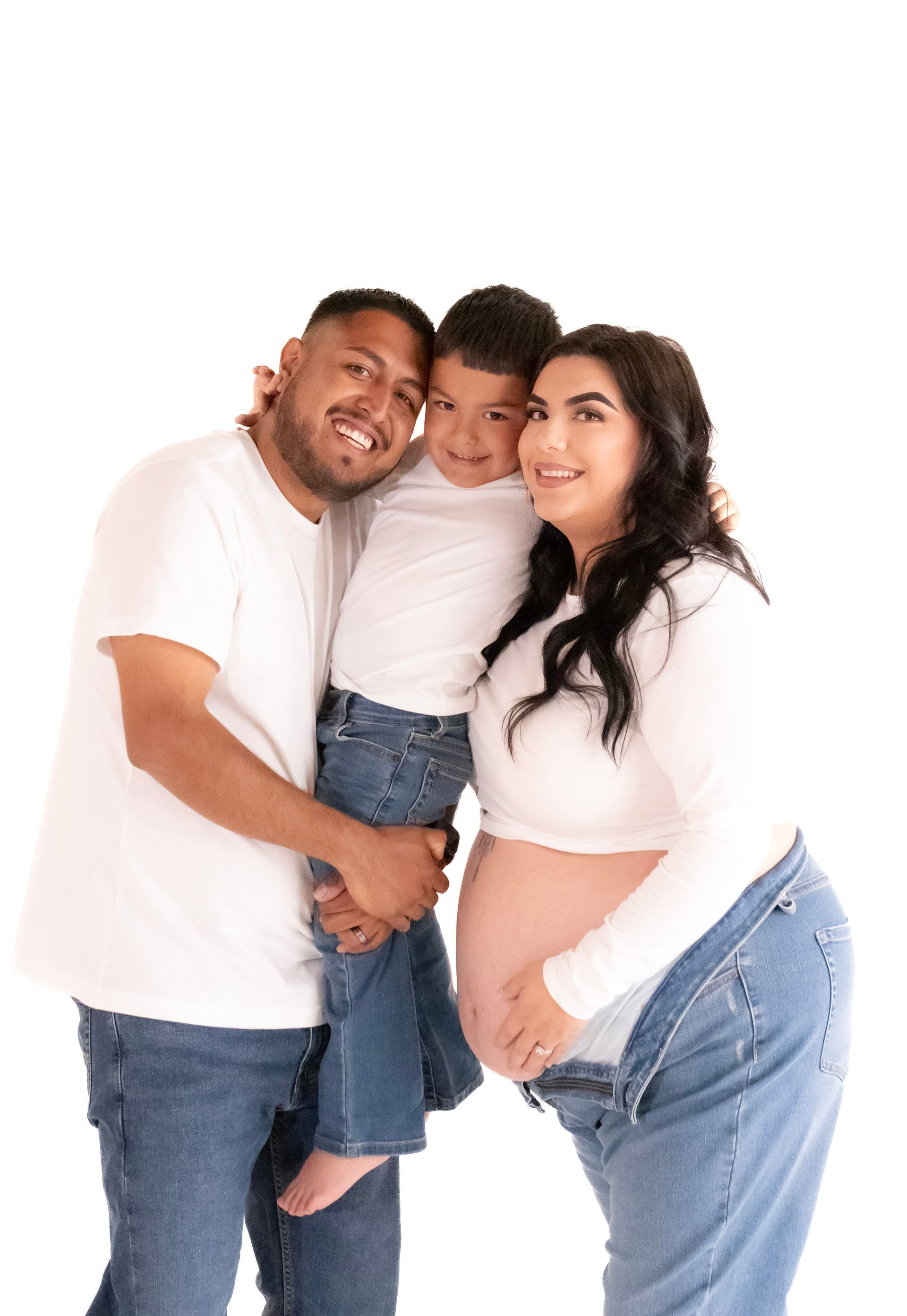 A pregnant woman is posing for a picture with her husband and son.