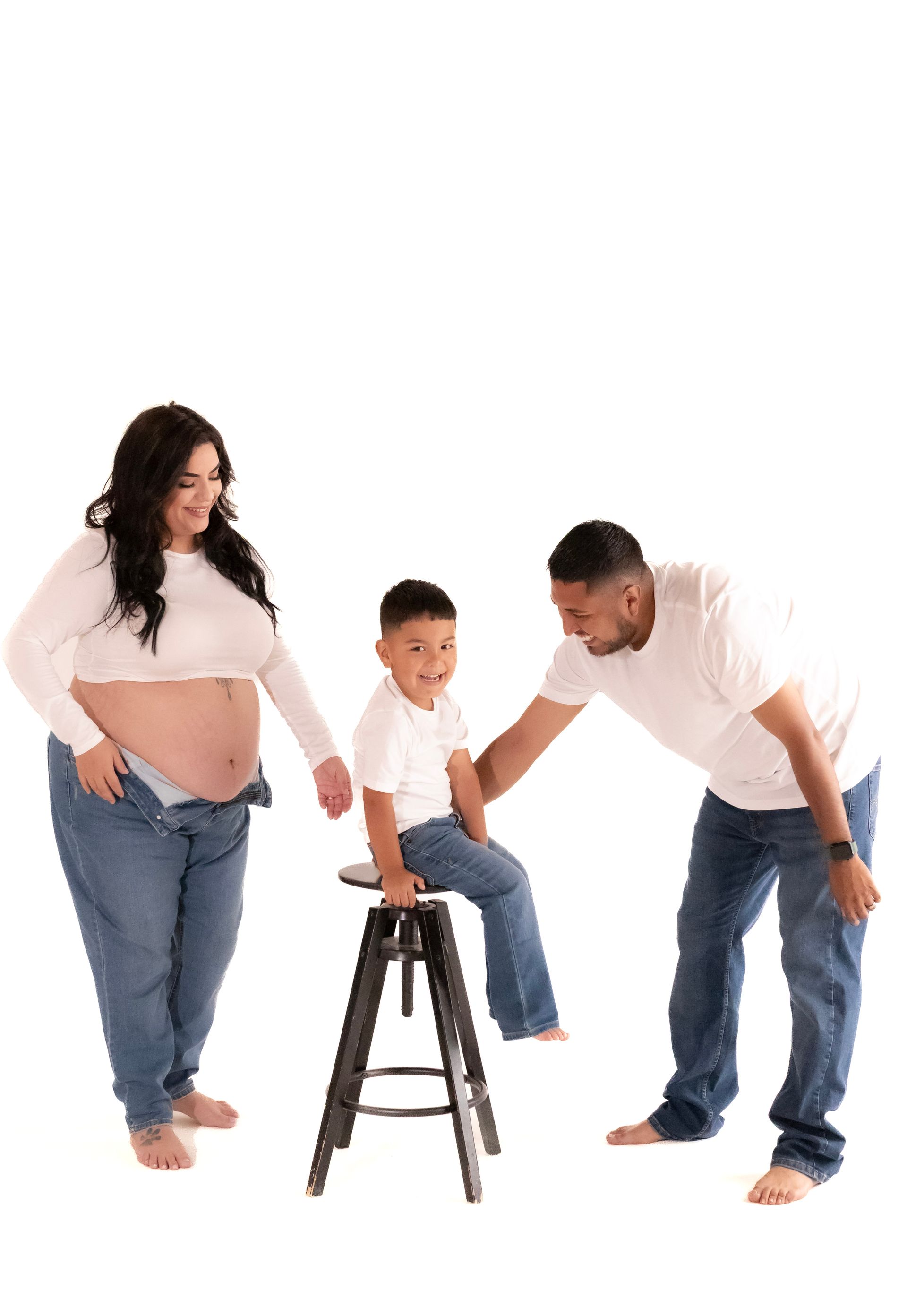A pregnant woman , a man and a child are posing for a picture.