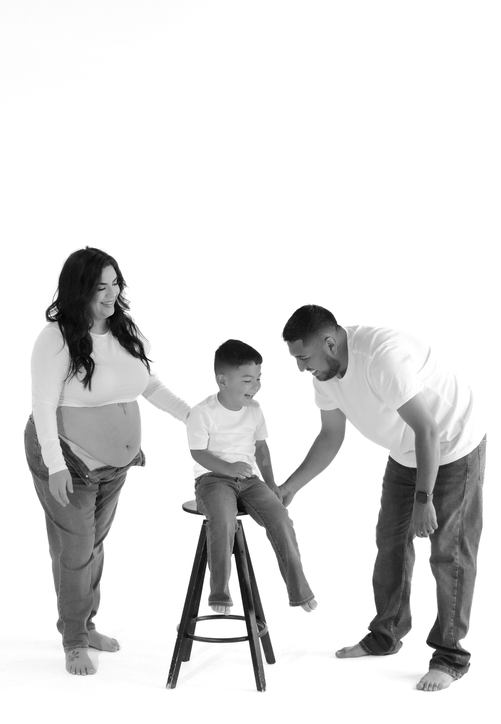 A black and white photo of a pregnant woman , a man and a child.