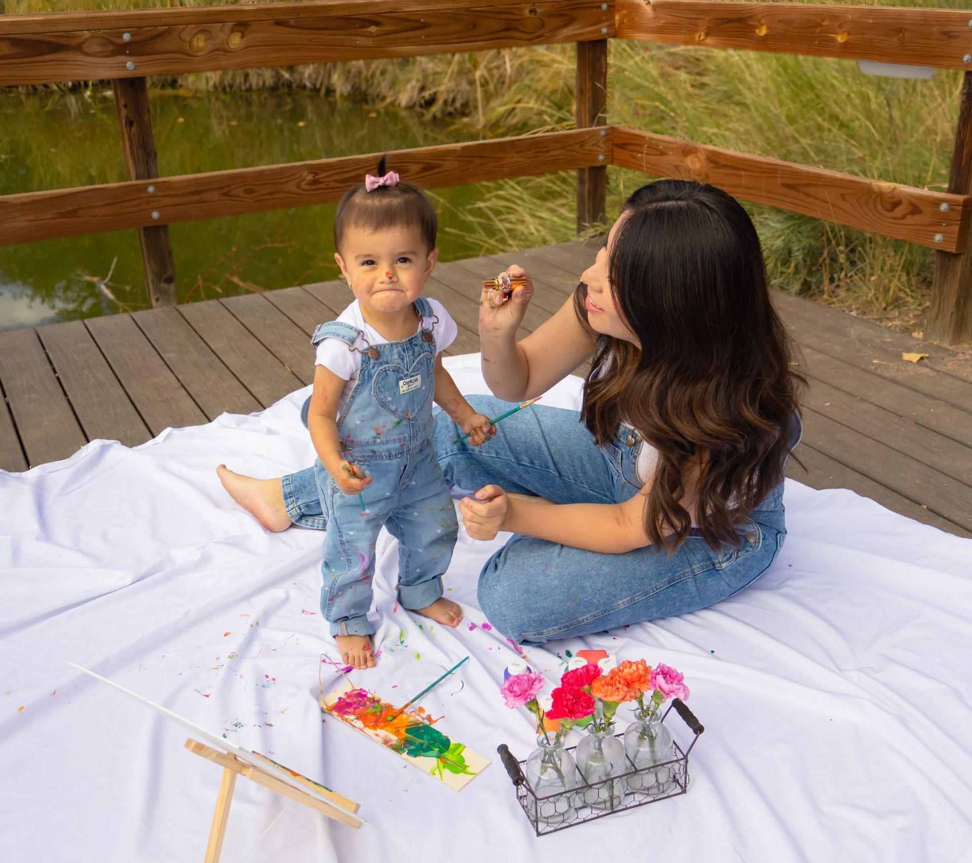 A woman and a little girl are sitting on a blanket.