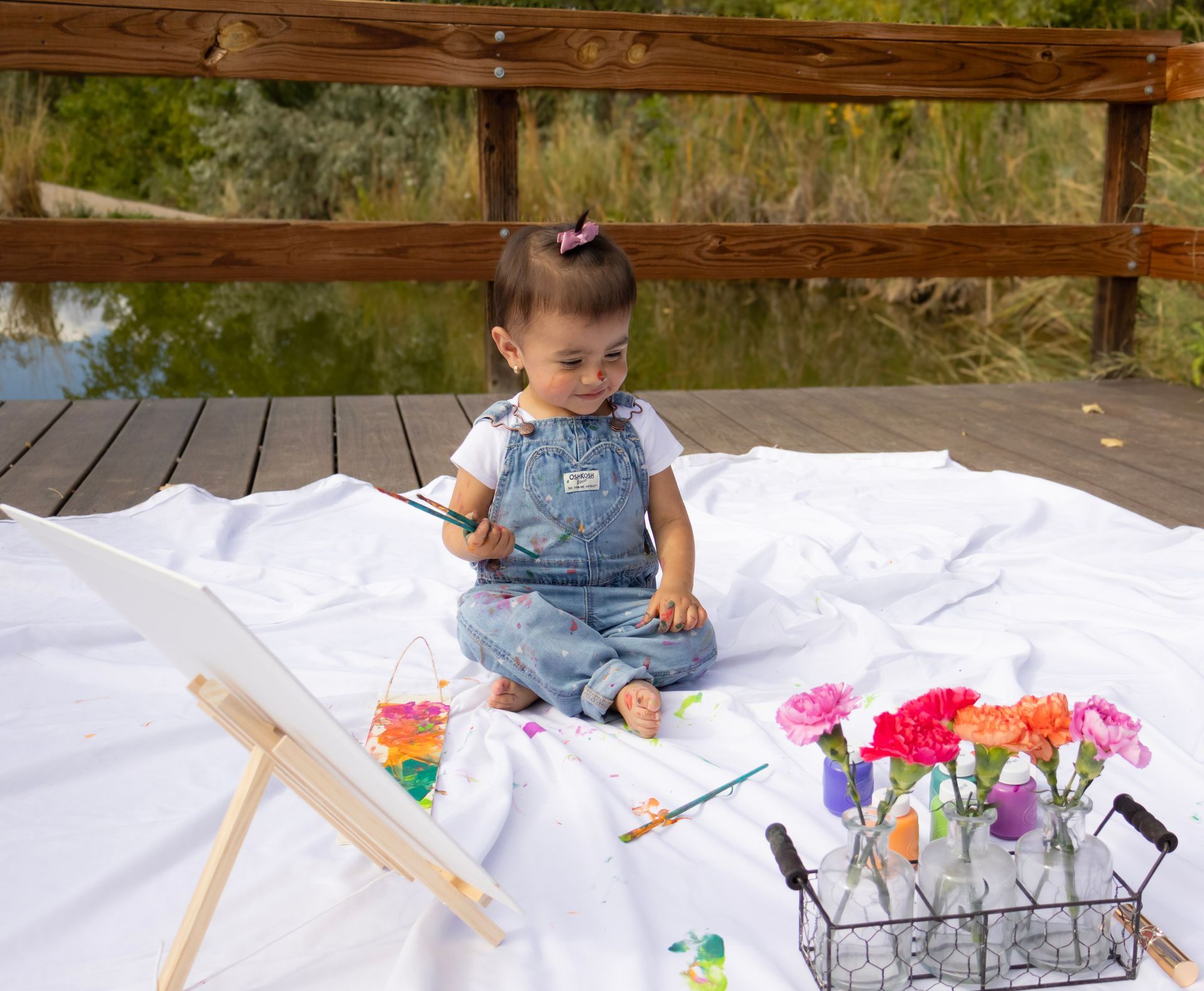 A little girl is sitting on a blanket painting flowers.