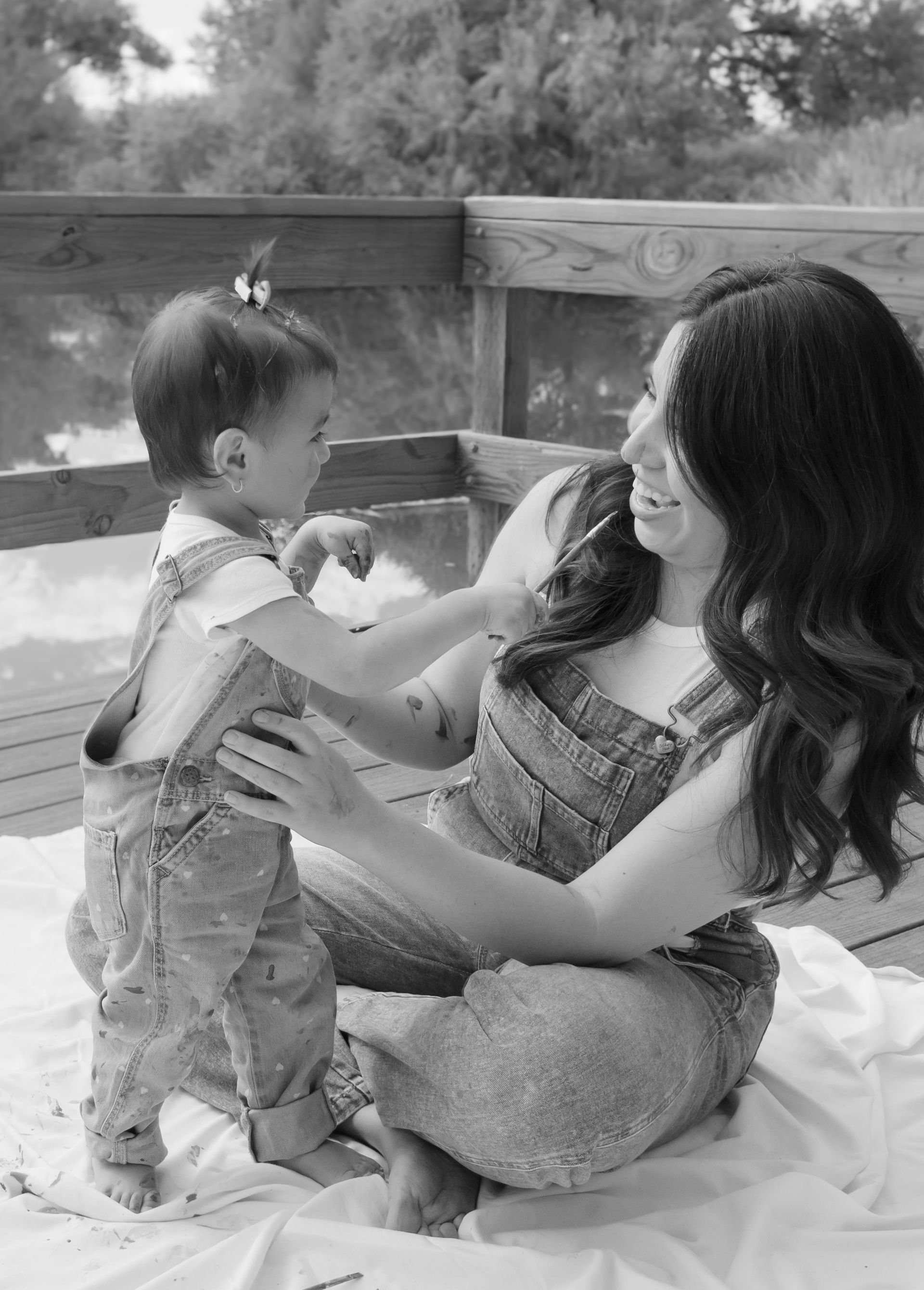 A woman is sitting on a blanket holding a baby.