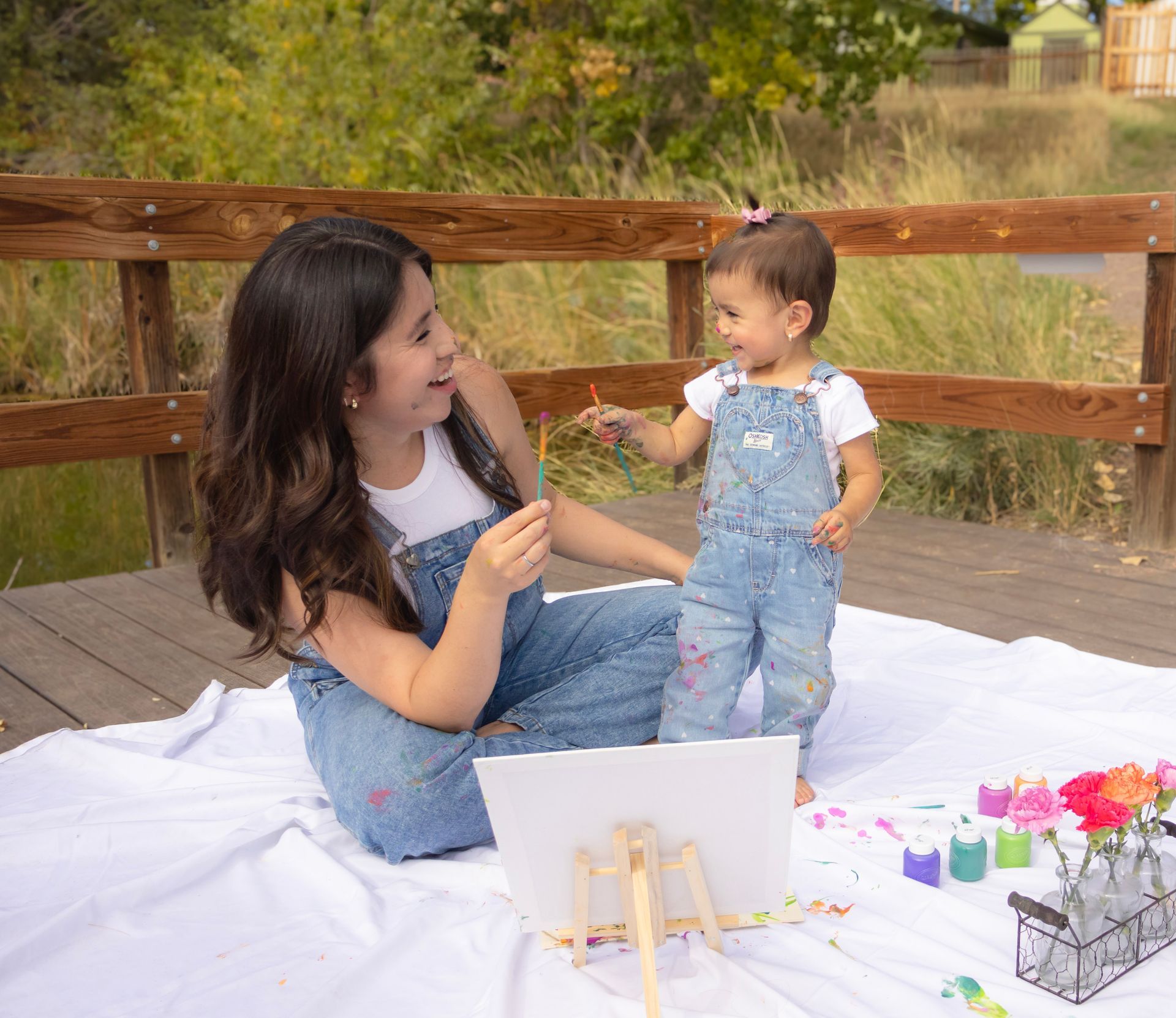 A woman and a little girl are sitting on a blanket.