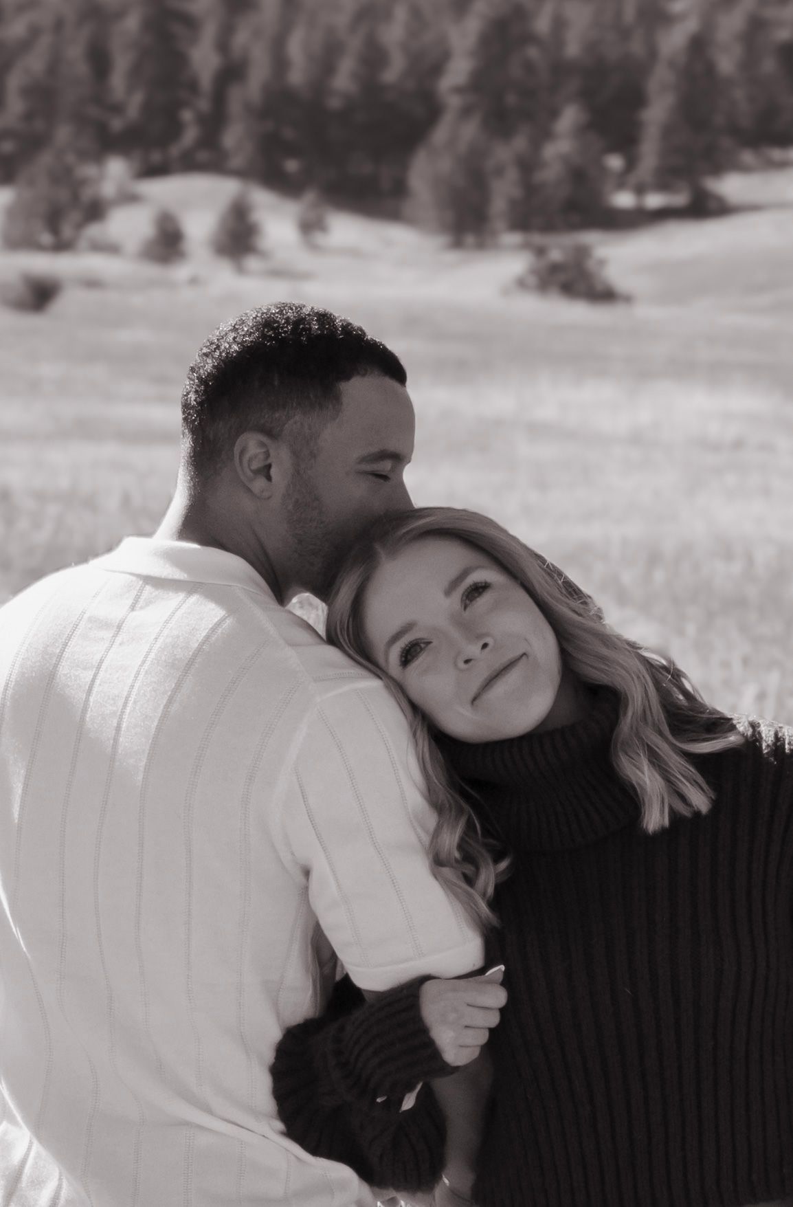 A man is kissing a woman on the forehead in a black and white photo.