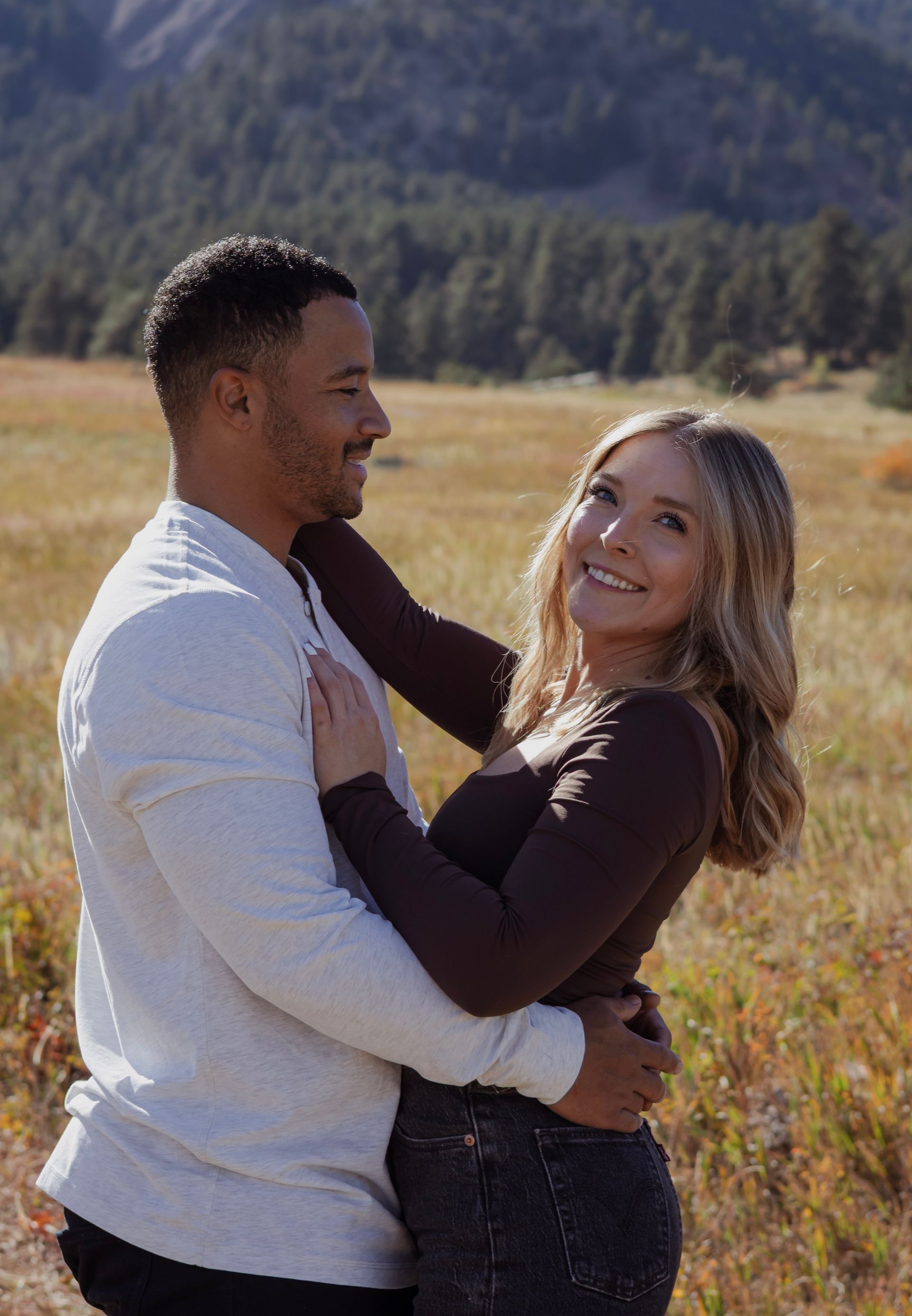 A man and a woman are hugging each other in a field.