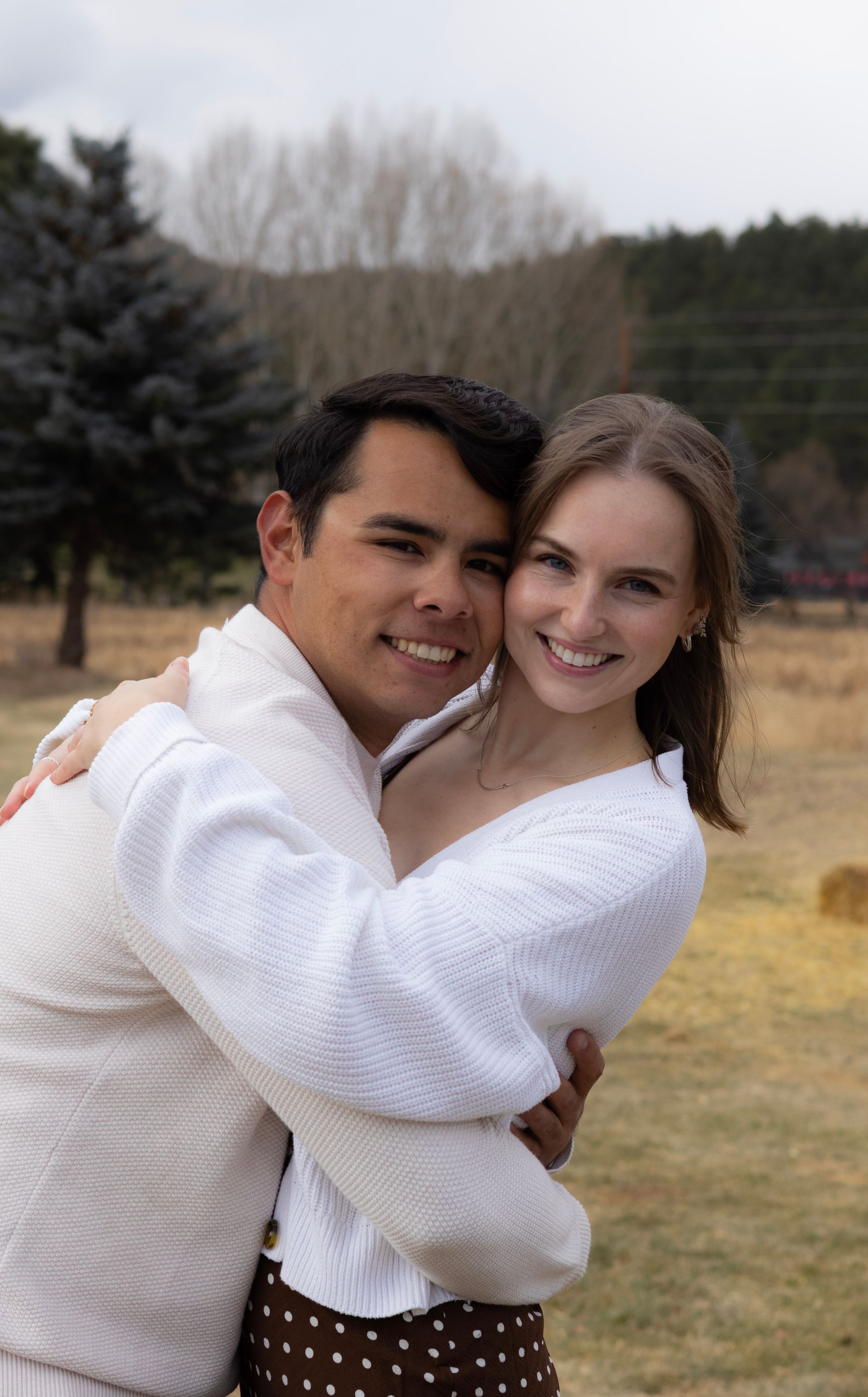 A man and a woman are hugging each other in a field.