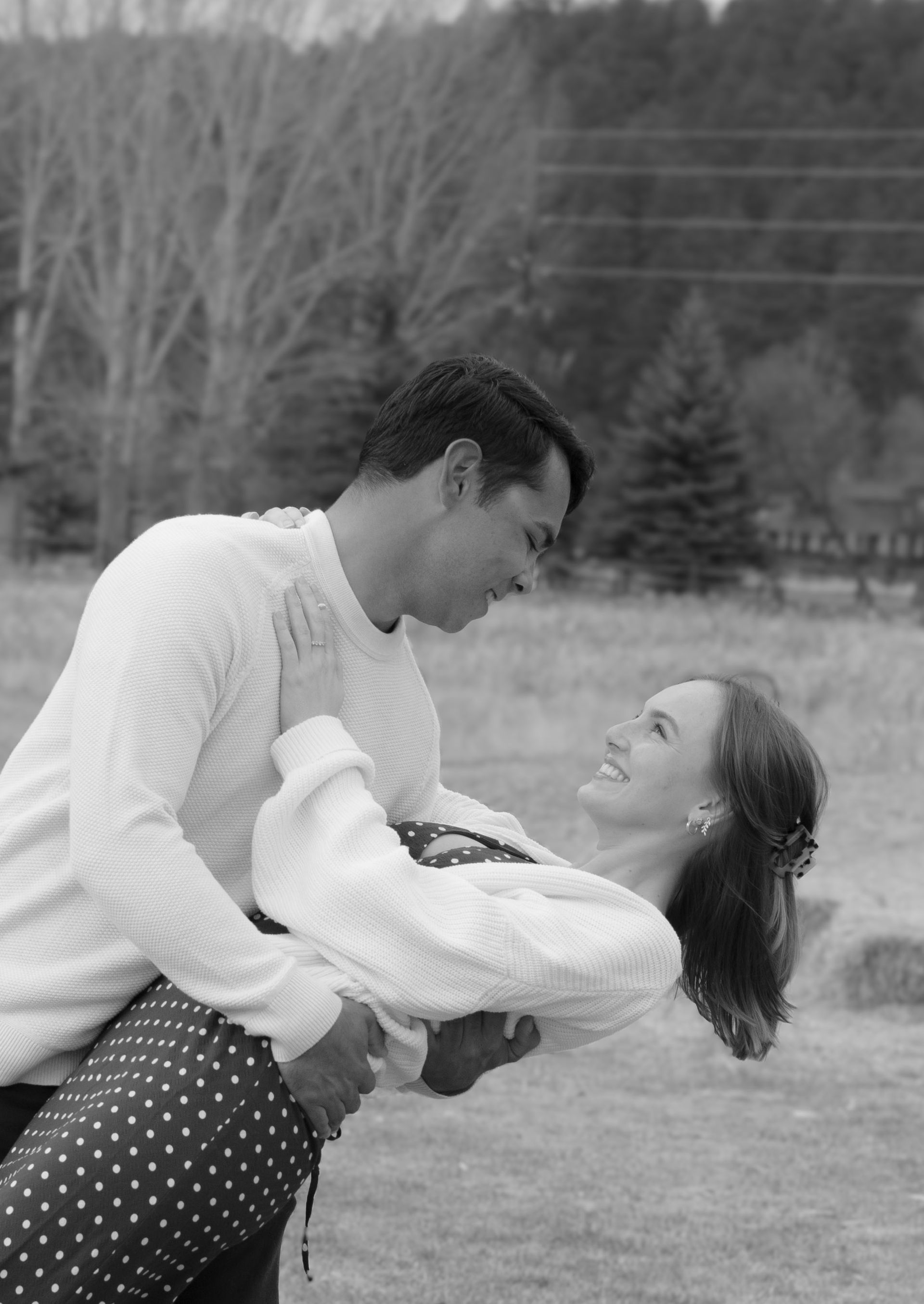A man is holding a woman in his arms in a black and white photo.