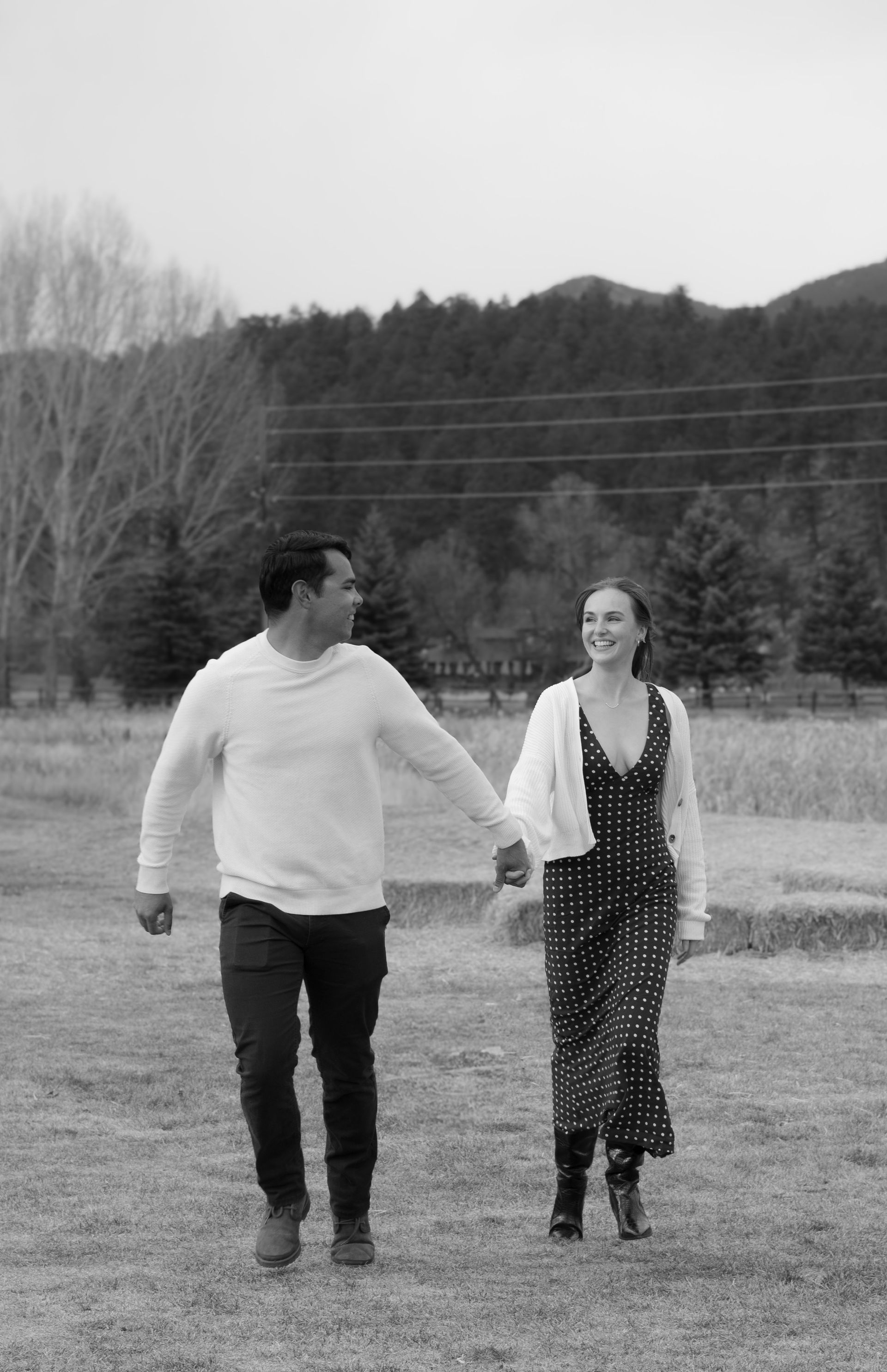 A man and a woman are holding hands while walking through a field.