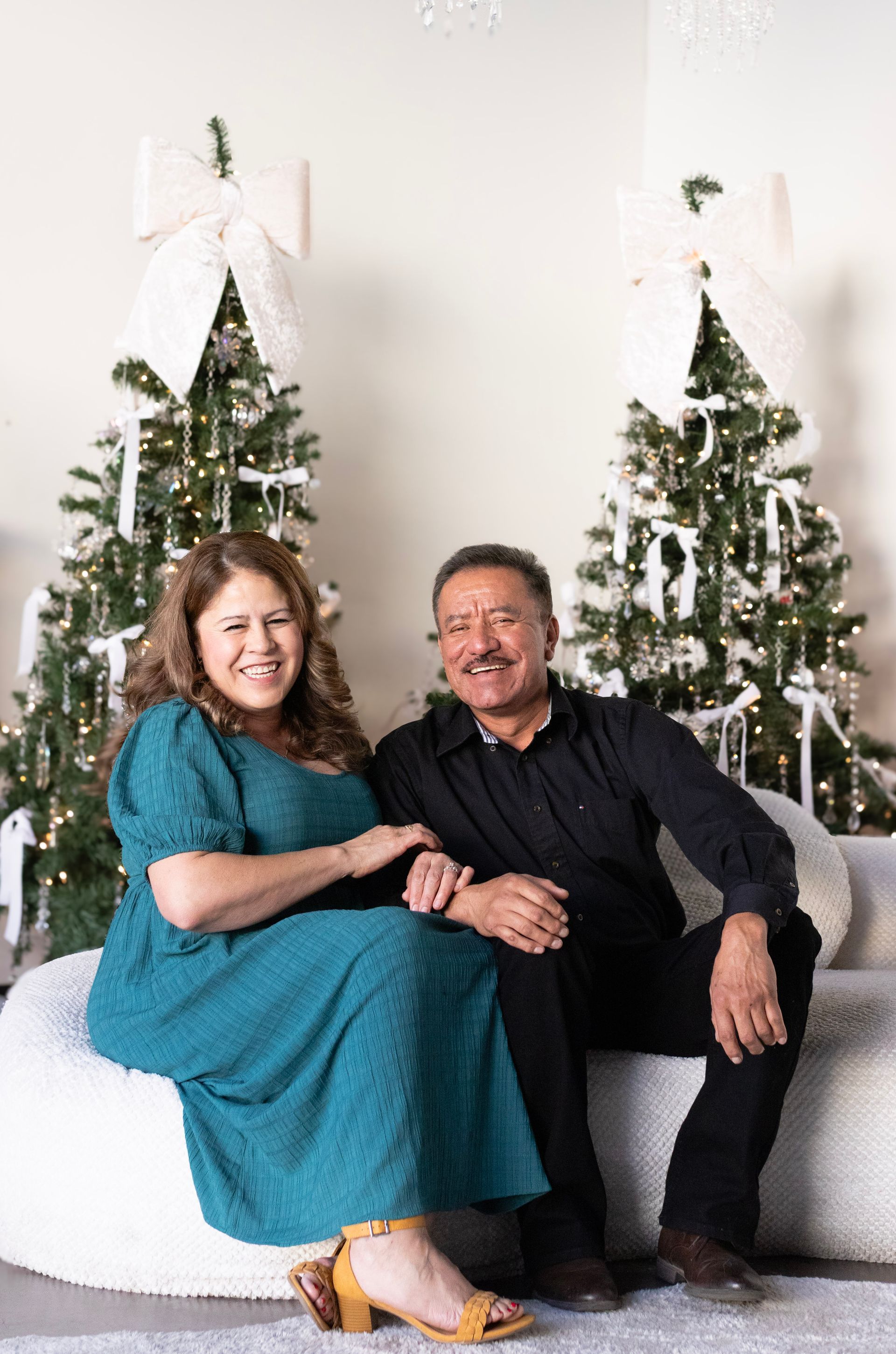 A man and a woman are sitting on a couch in front of a christmas tree.