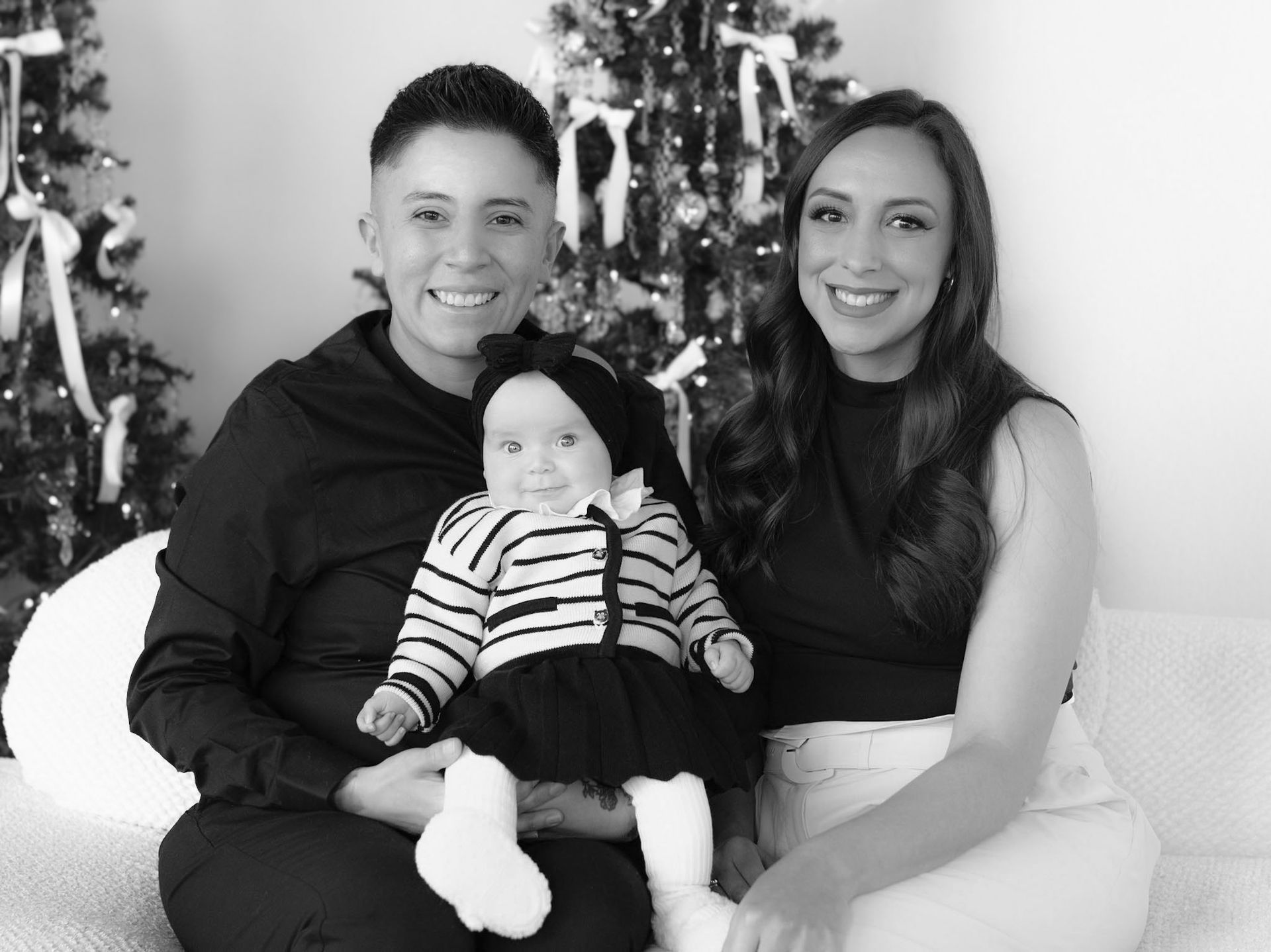 A family is posing for a picture in front of a christmas tree.