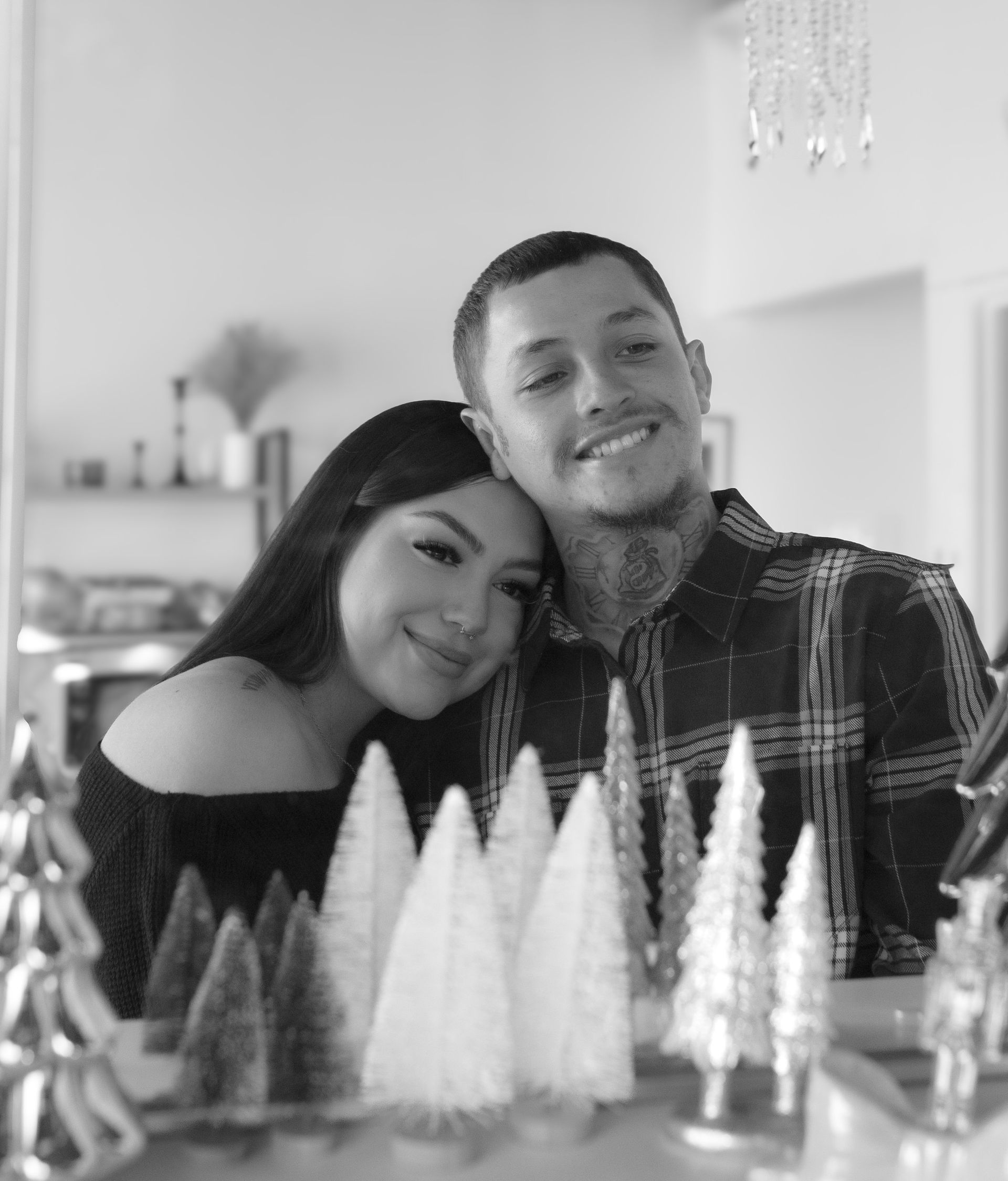 A man and a woman are posing for a picture with christmas trees in the background.