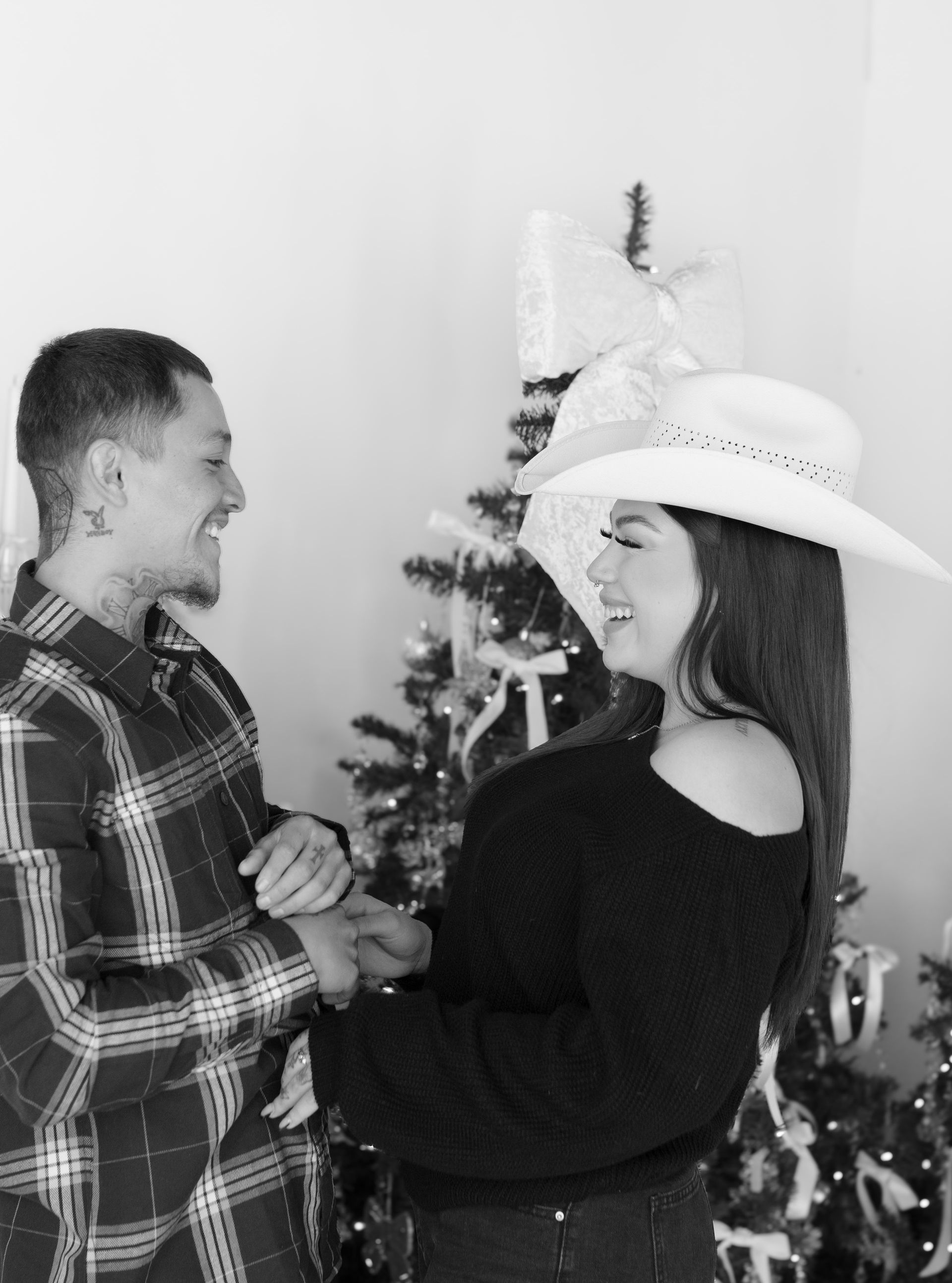 A man and a woman are holding hands in front of a christmas tree.