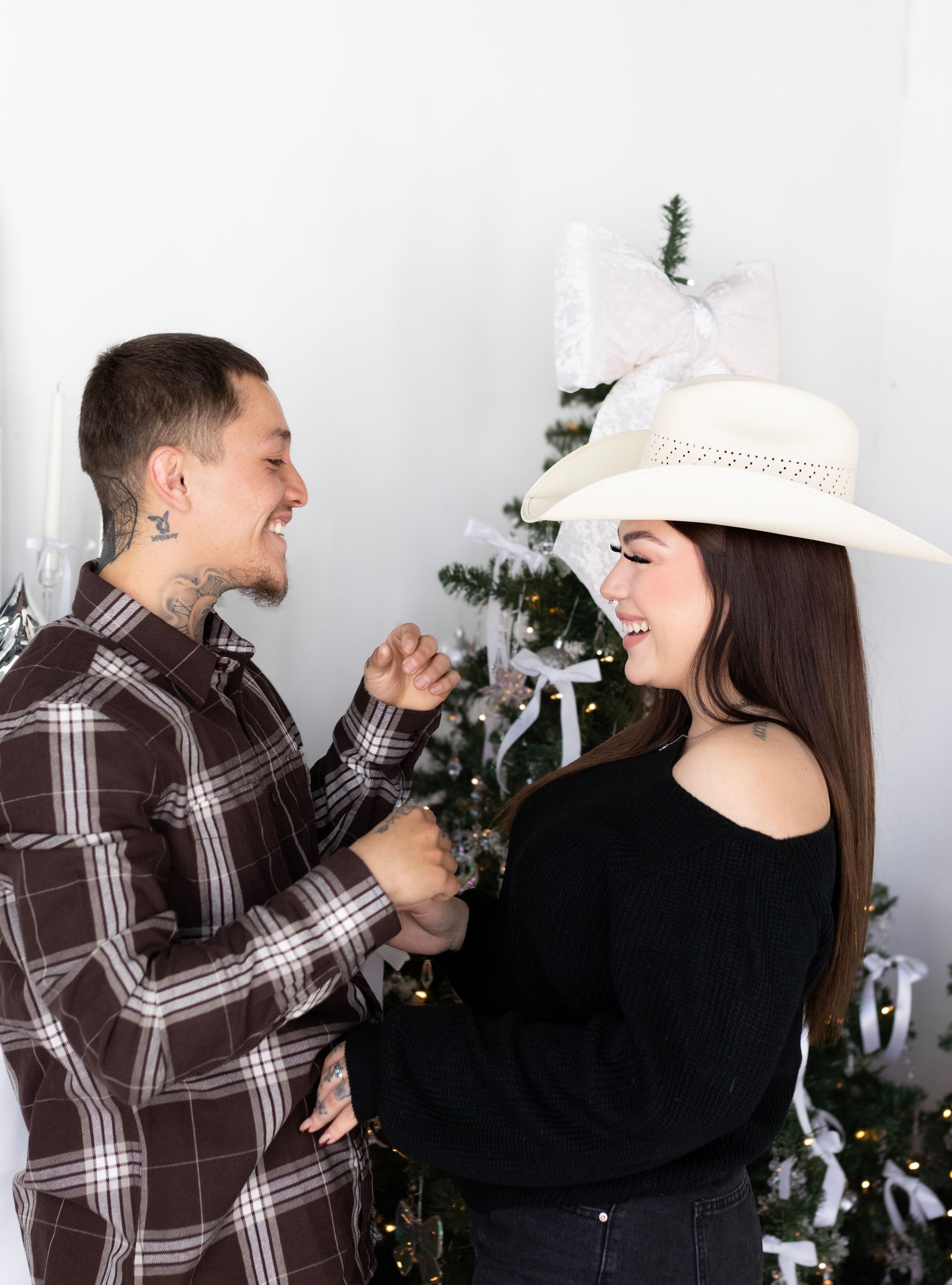 A man and a woman are holding hands in front of a christmas tree.