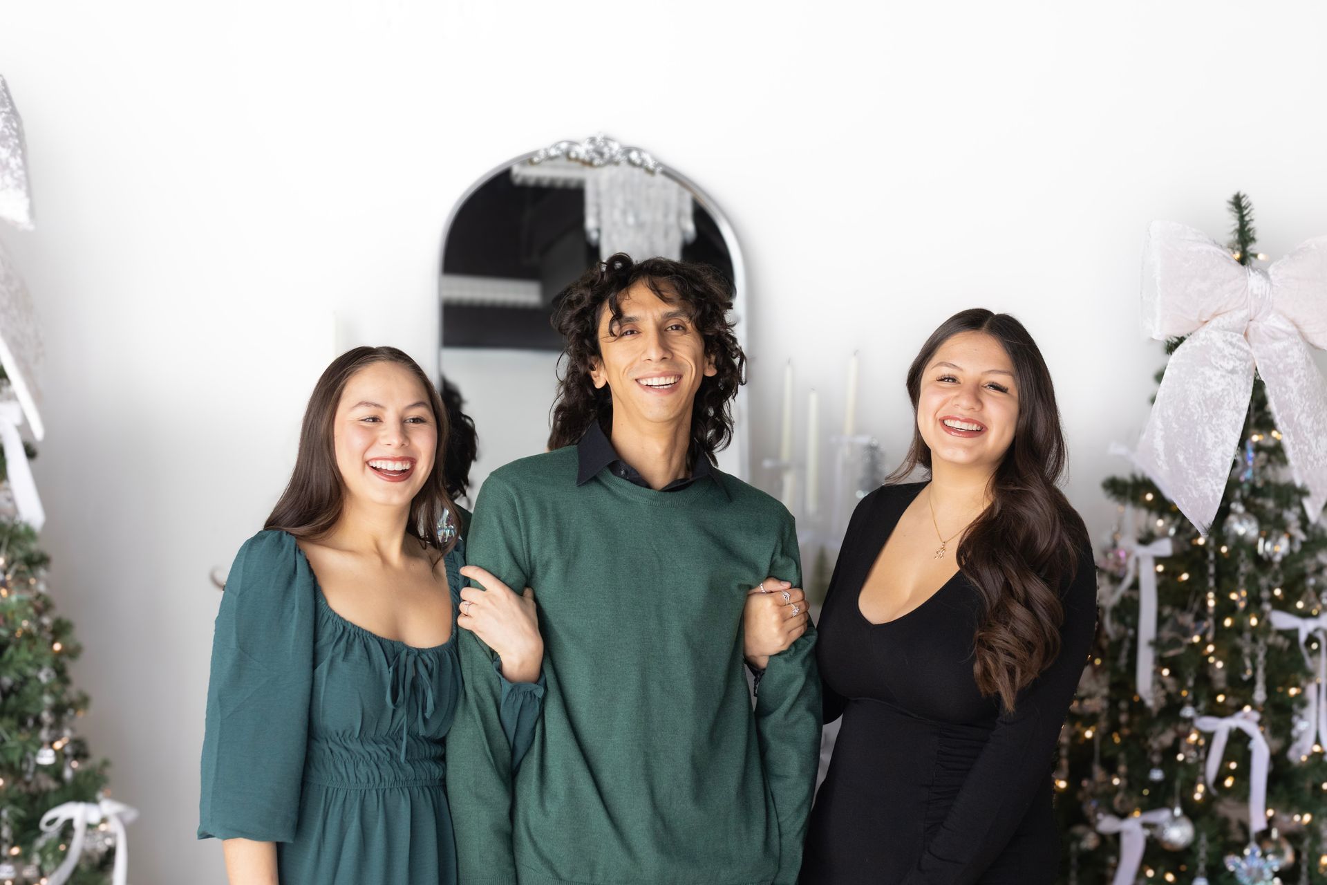 A man and two women are posing for a picture in front of a christmas tree.