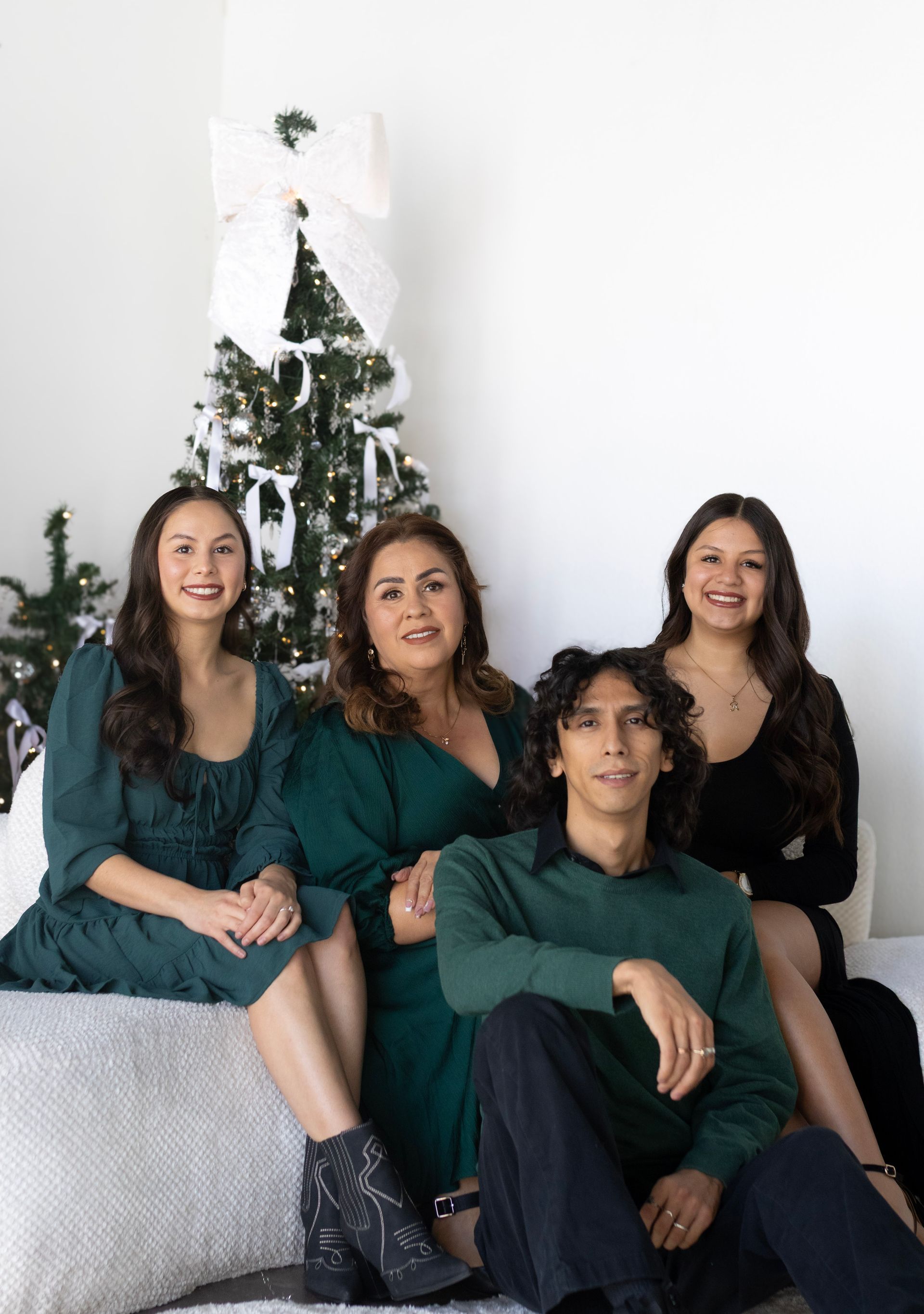 A family is posing for a picture in front of a christmas tree.