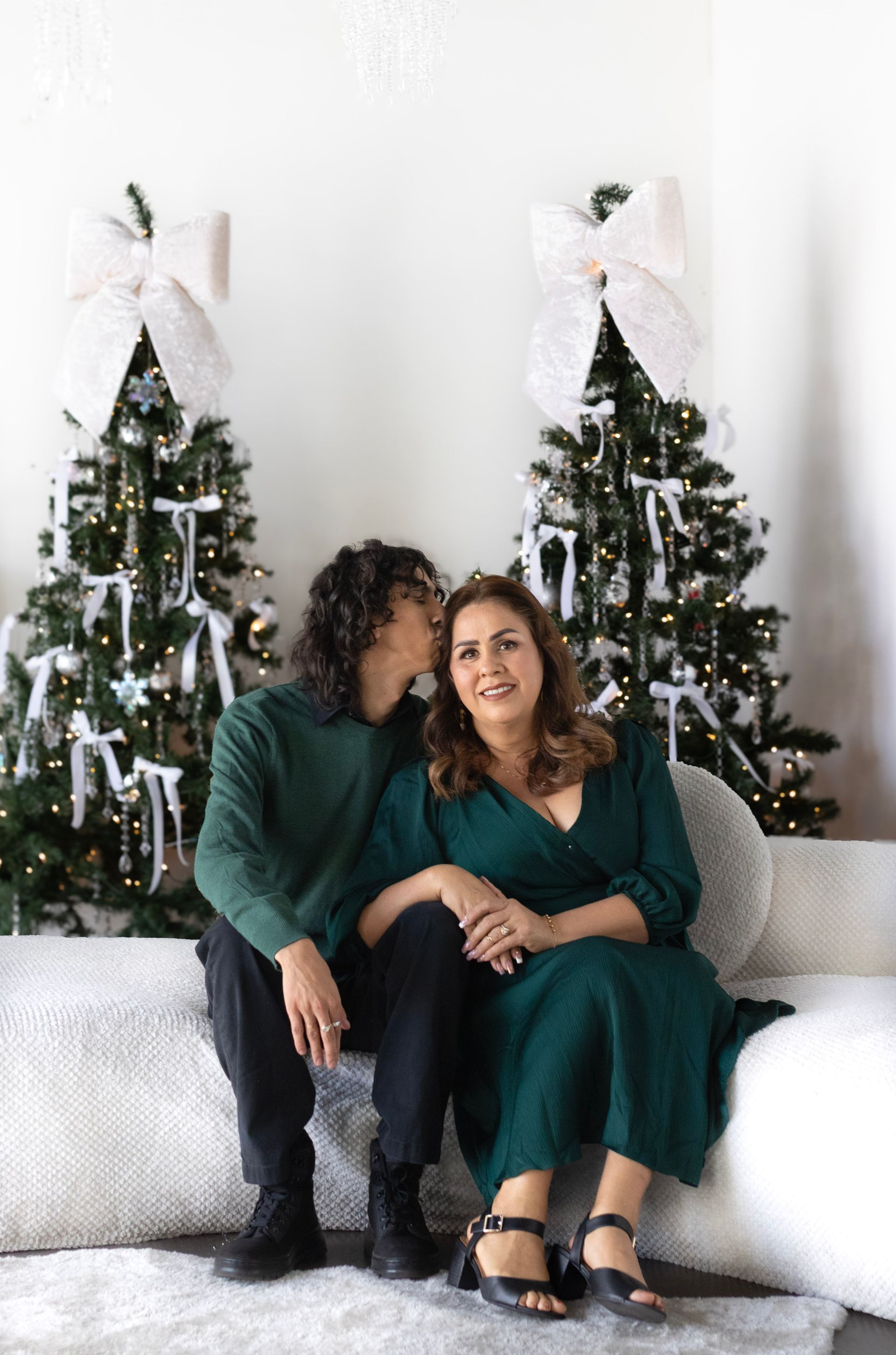 A man and a woman are sitting on a couch in front of a christmas tree.
