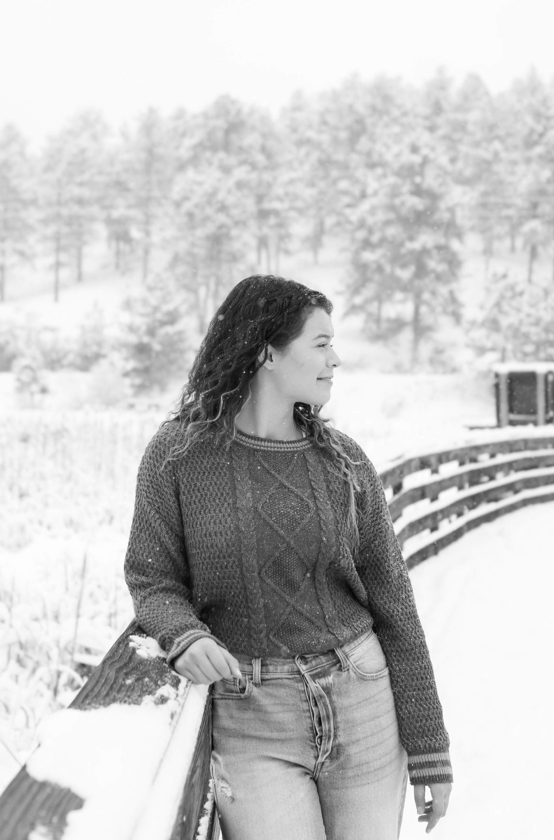 A woman is leaning on a railing in the snow.