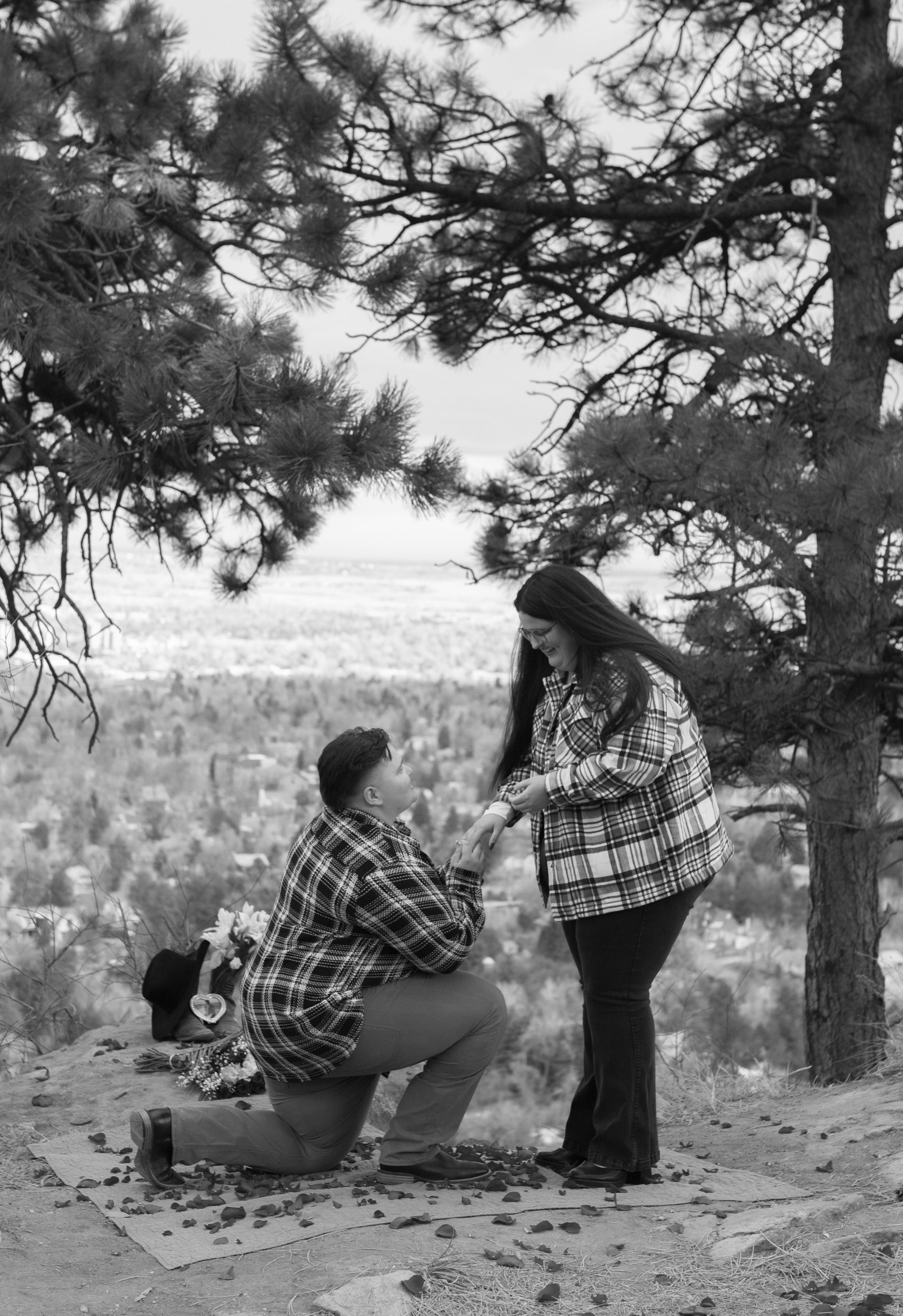 A man is kneeling down to propose to a woman in a black and white photo.