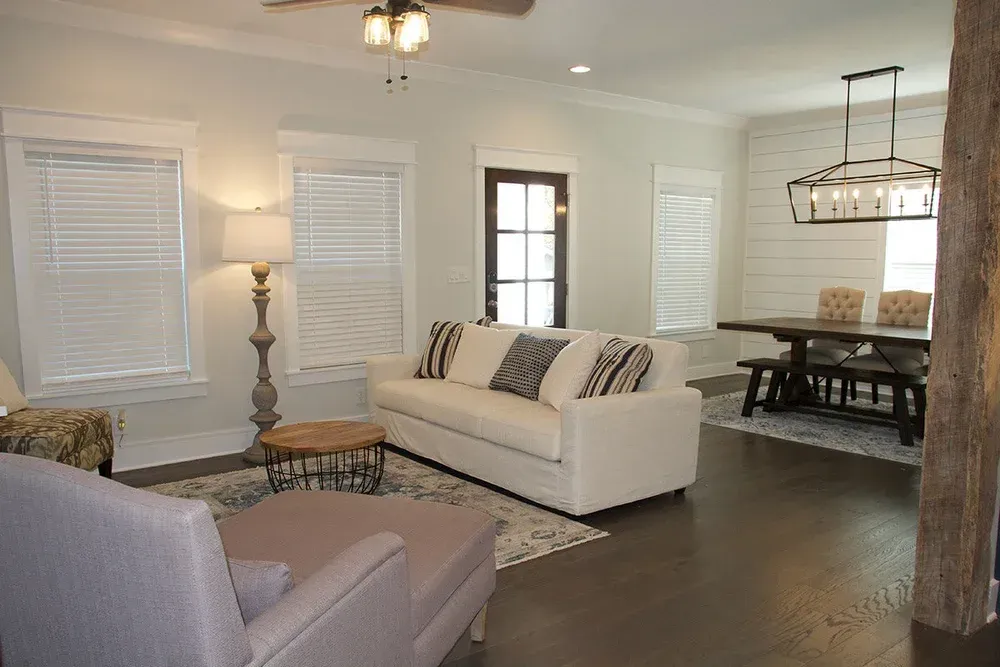 Living room with white sofa, round coffee table, dining table, and dark hardwood floors.