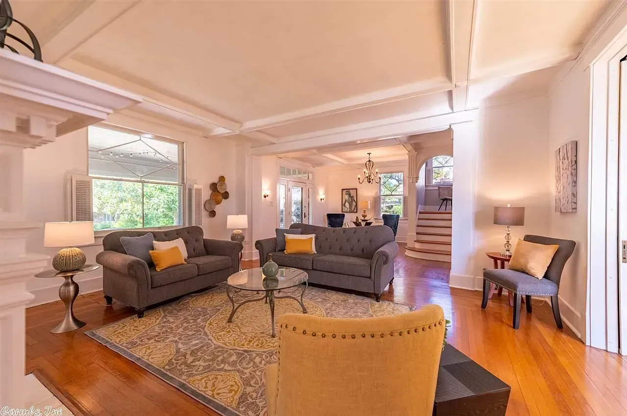 Living room with two gray sofas, wood floors, and ornate ceiling details.