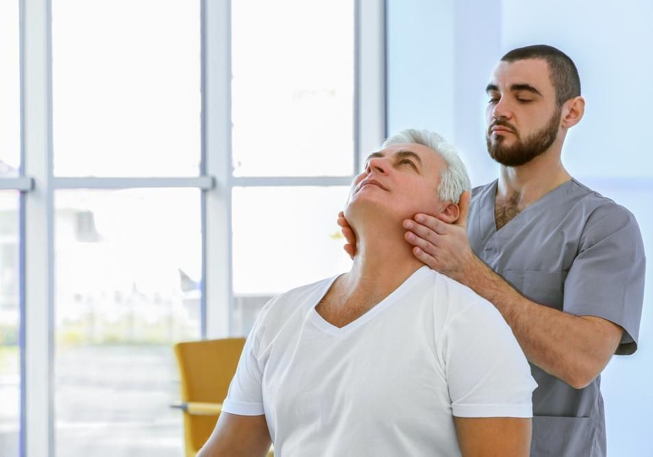 A Man Is Giving An Older Man A Neck Massage In A Hospital — Pin Point Remedial Massage In Lammermoor, QLD