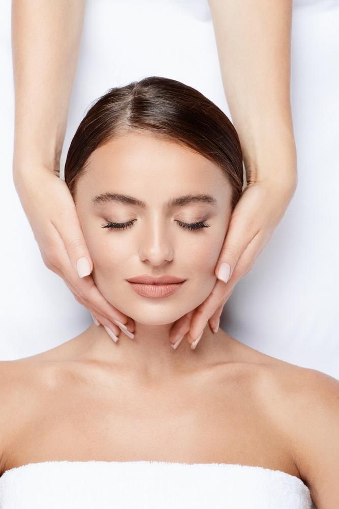 A Woman Is Getting A Facial Massage In A Spa — Pin Point Remedial Massage In Lammermoor, QLD