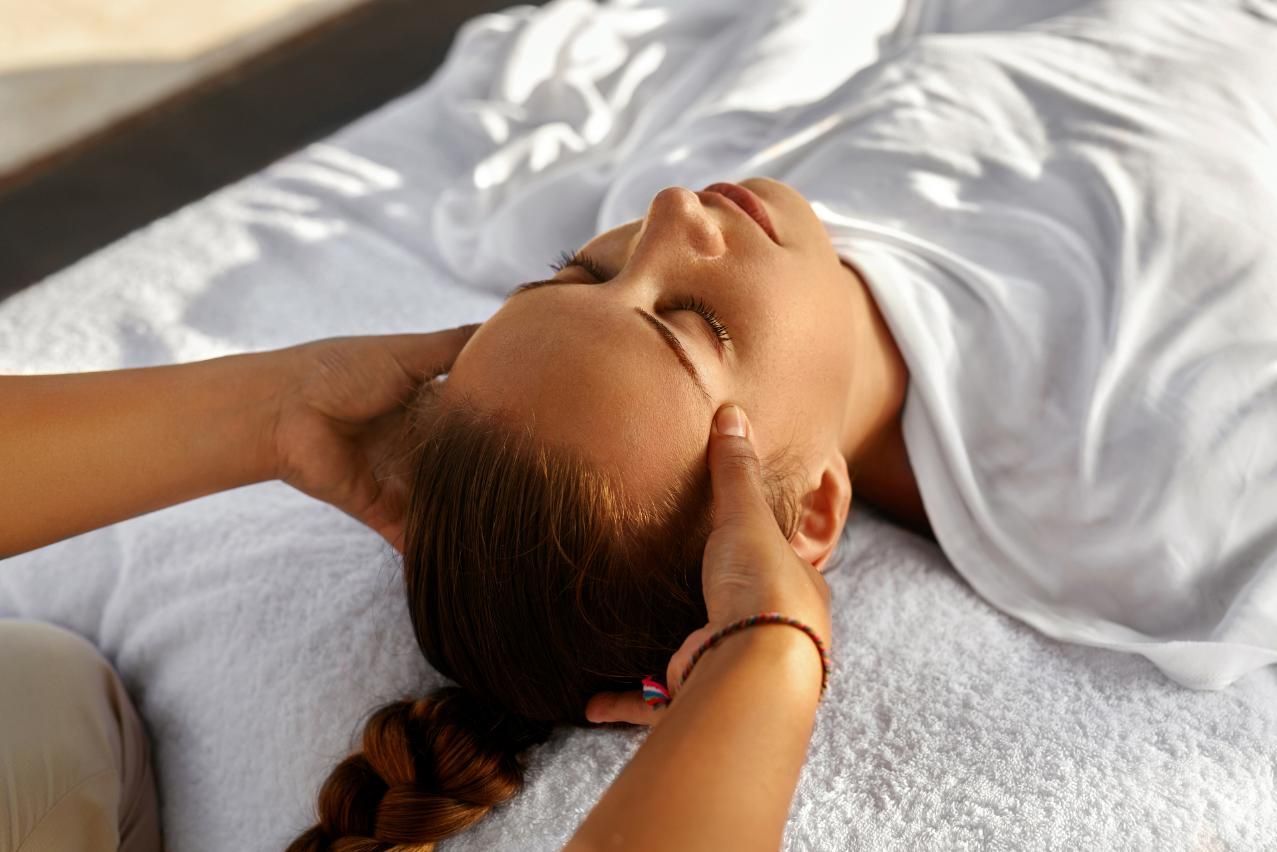 A Woman Is Laying On A Bed Getting A Head Massage — Pin Point Remedial Massage In Lammermoor, QLD