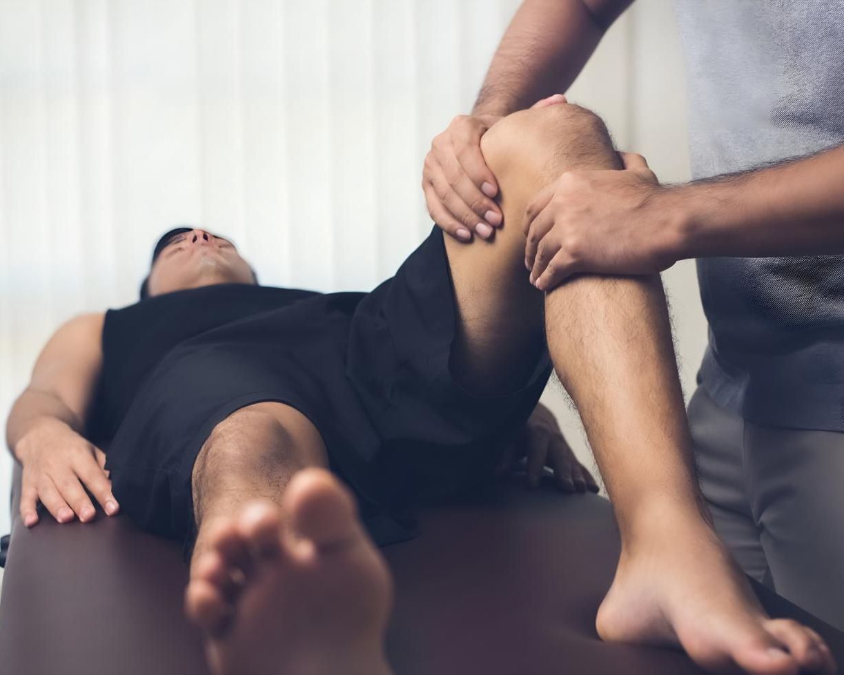A Man Is Laying On A Table Getting A Massage On His Knee — Pin Point Remedial Massage In Lammermoor, QLD