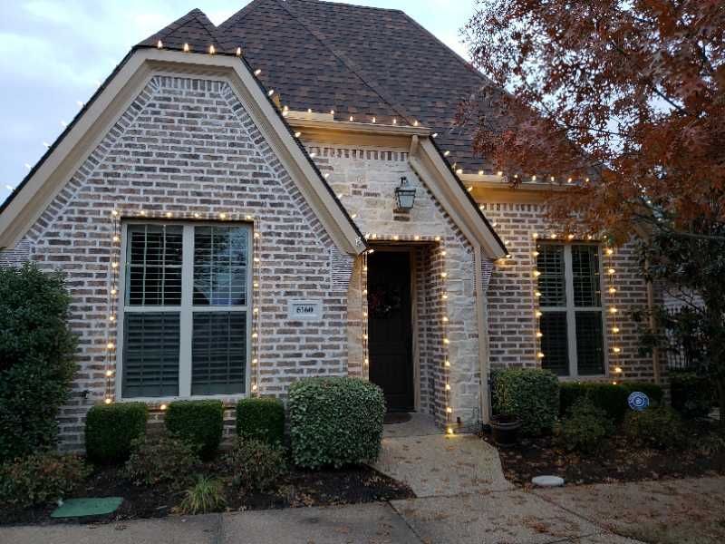 House decorated with white Christmas lights on brick exterior.
