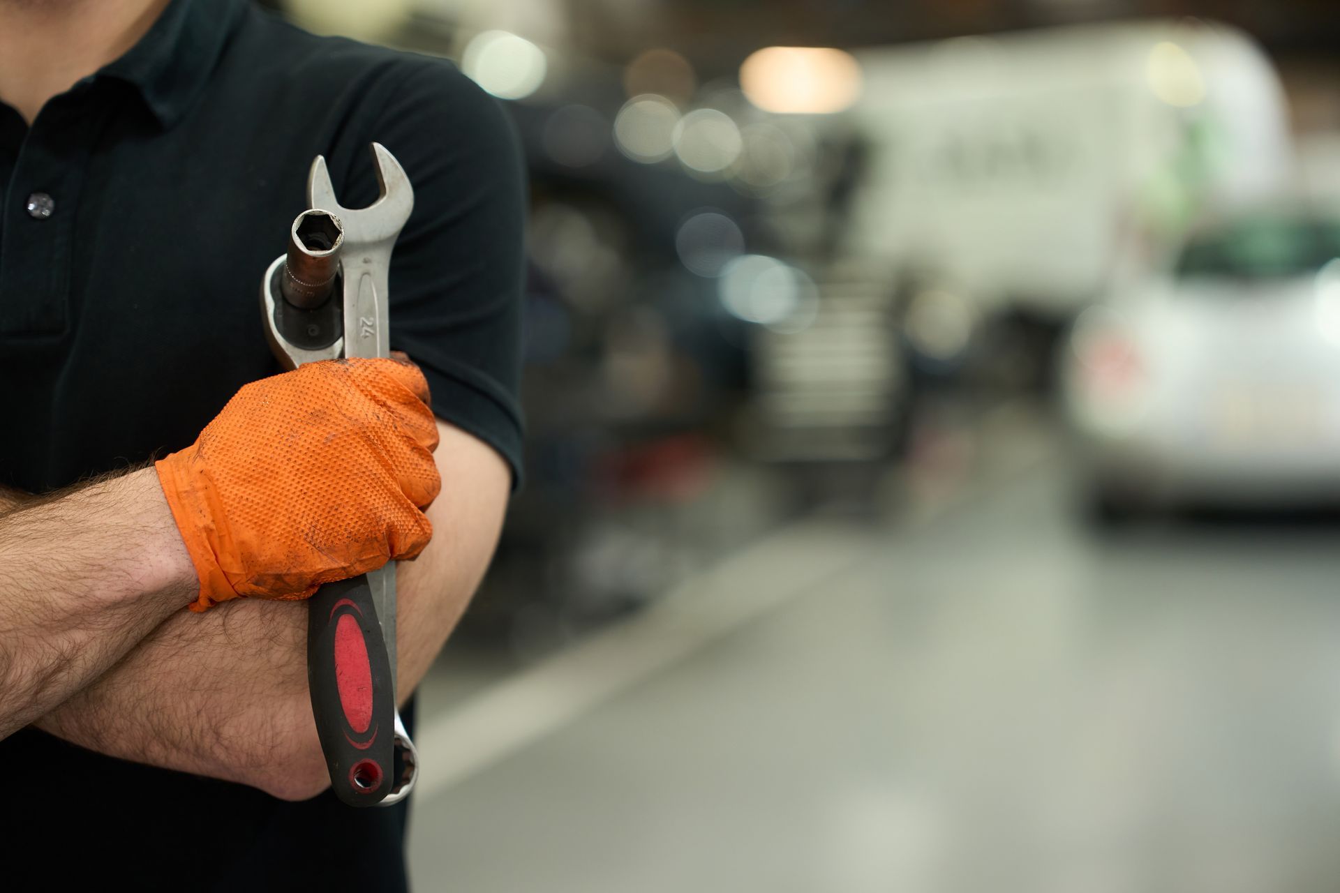 Mechanic holding wrench and socket in garage.