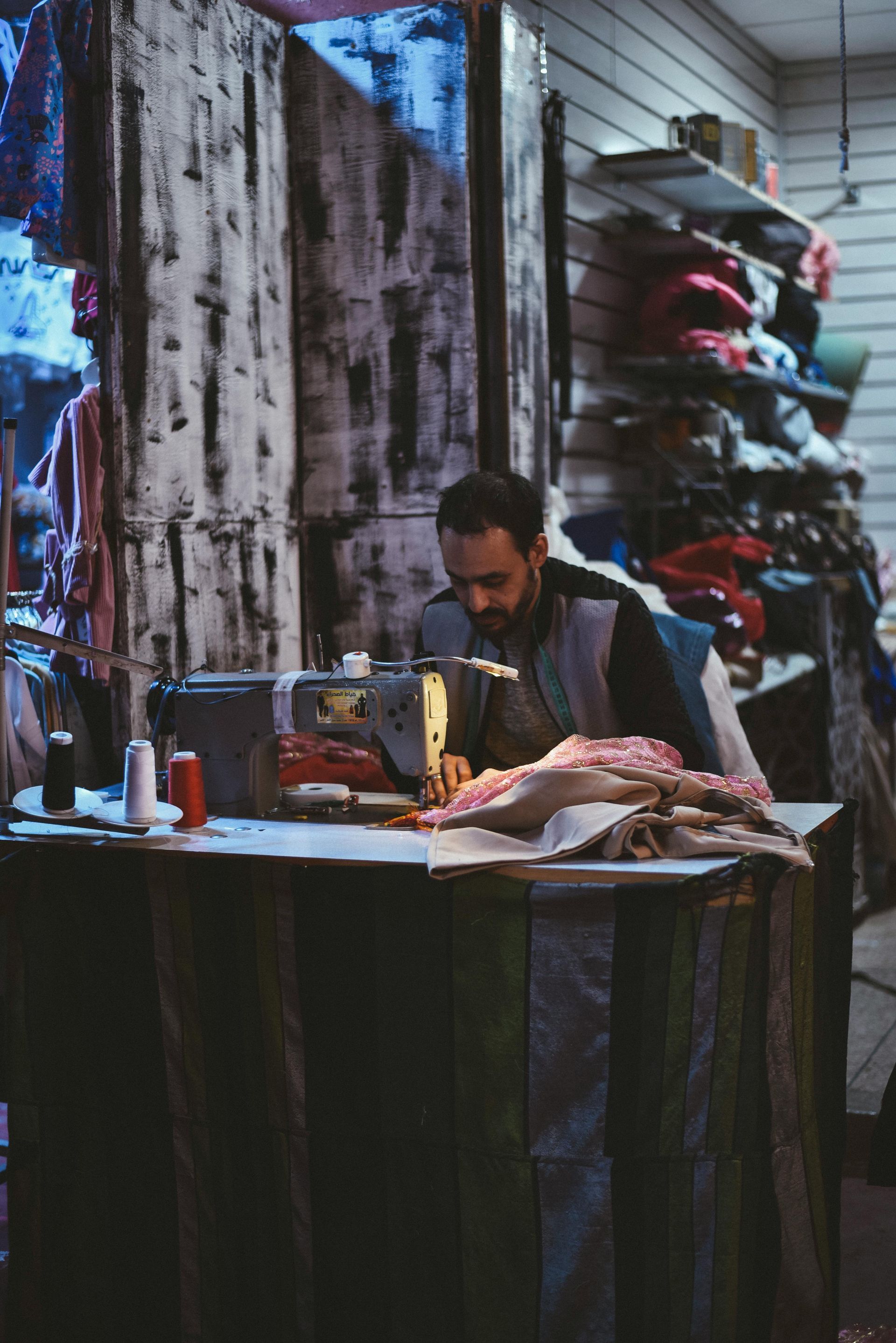 A man is sitting at a table using a sewing machine.