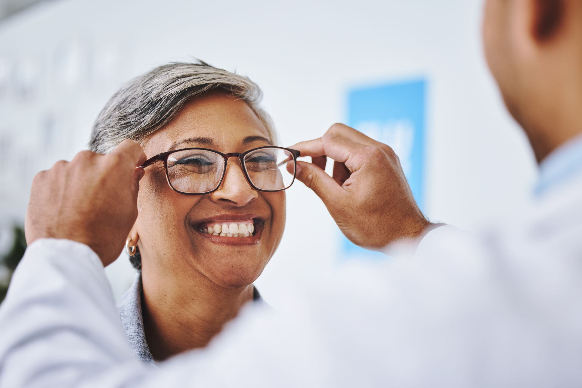 Smiiling woman getting glasses fitted by an expert providing comprehensive optometrist services.