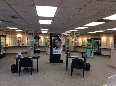 Interior of an optical shop with eyeglasses displays, desks, and a GUESS advertisement. Interior of an optical shop with eyeglasses displays, desks, and a GUESS advertisement.