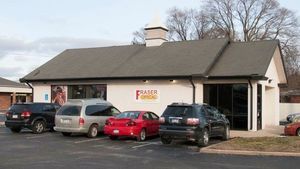 Exterior view of Fraser Funeral Home; cars parked in front of a white building with black trim.