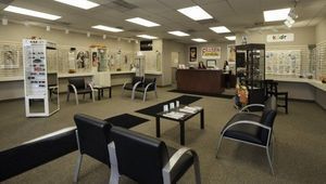 Interior of an optometry office, with seating, eyeglass displays, and a reception desk.