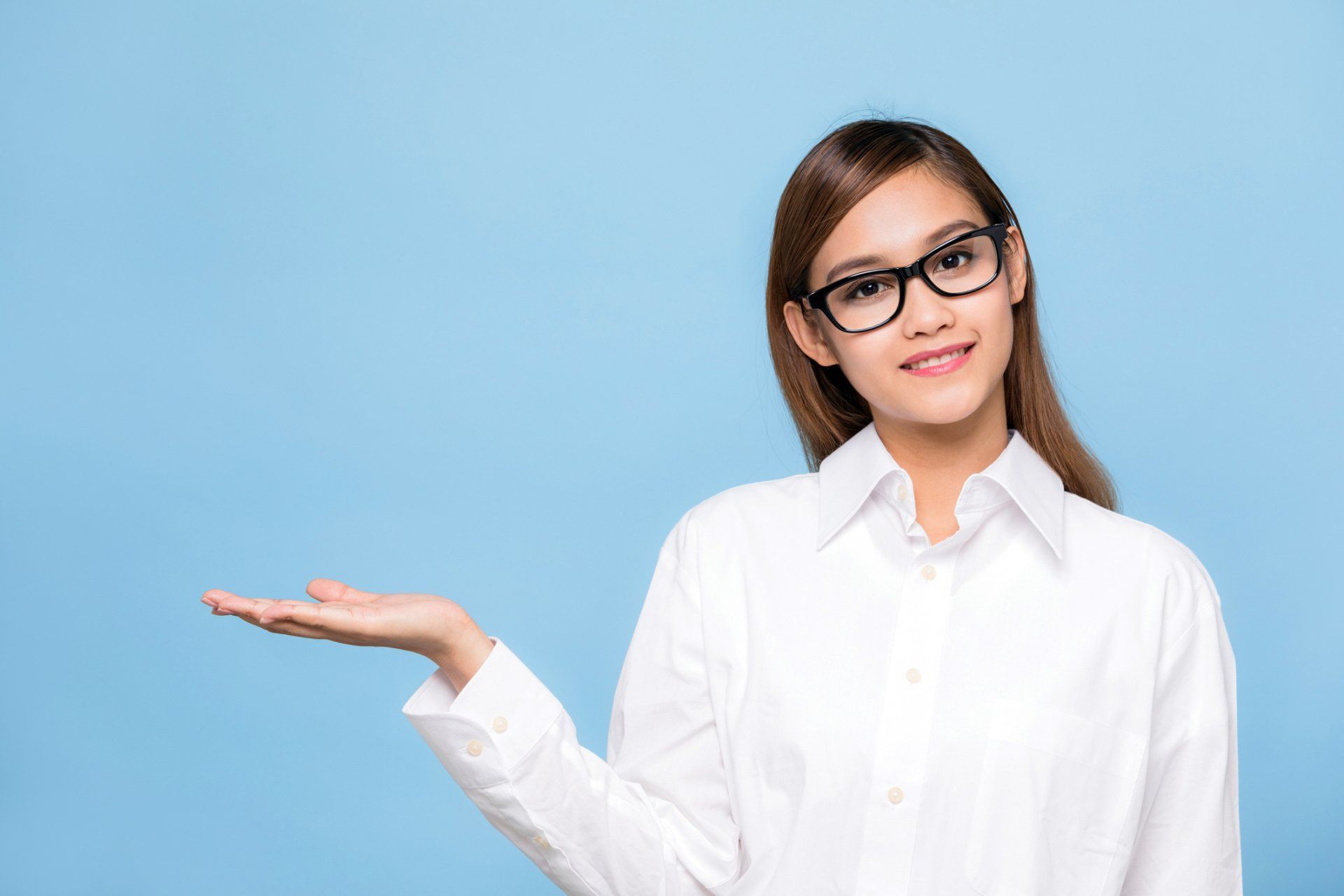 Woman with glasses and white shirt, smiling, extends hand, blue background. Woman with glasses and white shirt, smiling, extends hand, blue background.