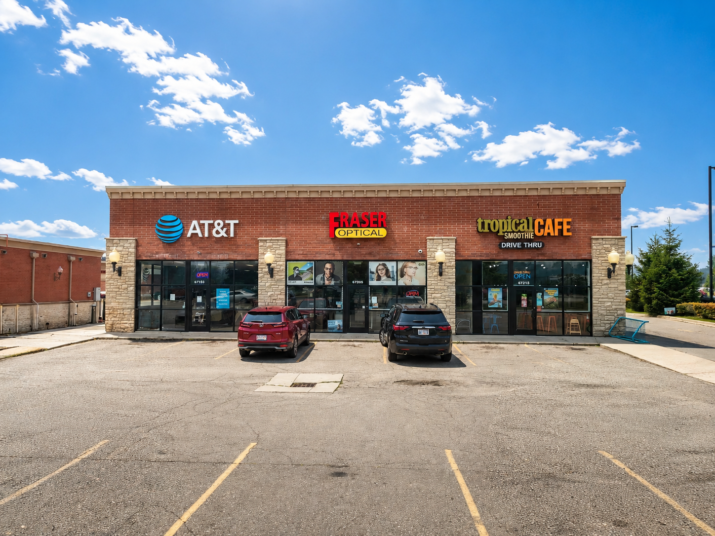 Fraser Optical store exterior with illuminated sign. A silver car is parked in front of the brick building.