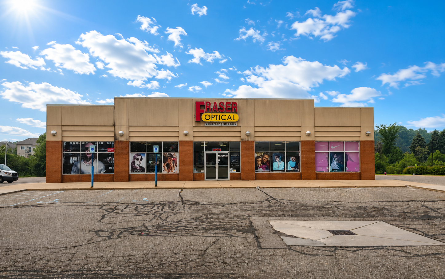 Fraser Optical store front with a dark green truck parked in front; clear sky.