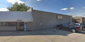 Exterior view of a commercial building with a sign and a truck parked outside.