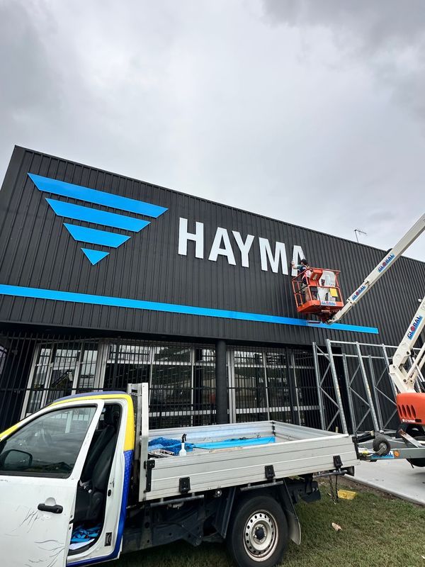 Sign Being Installed on a Dark Building — Millard Signs in Portsmith, QLD
