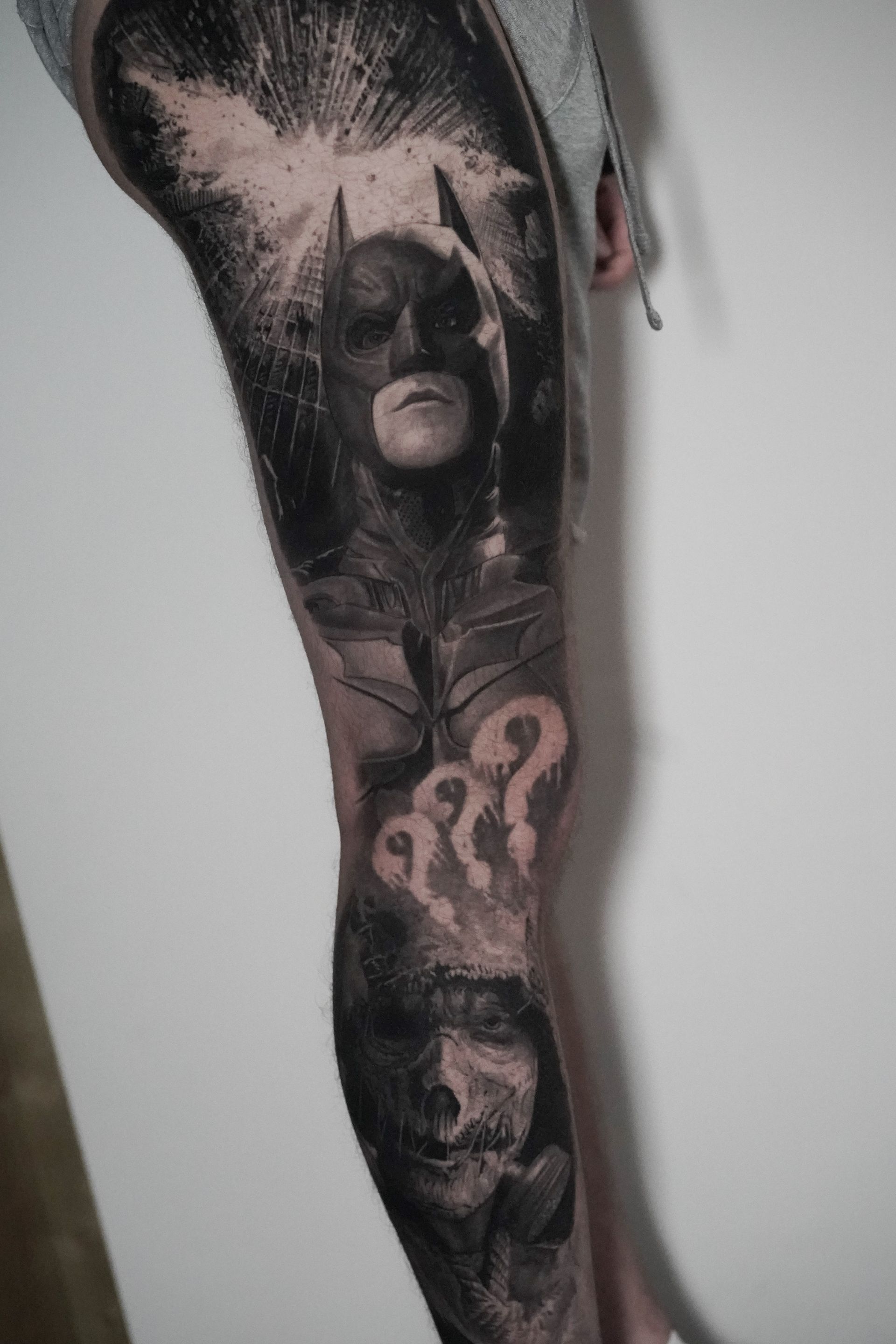 A person has a tattoo of batman on their leg.