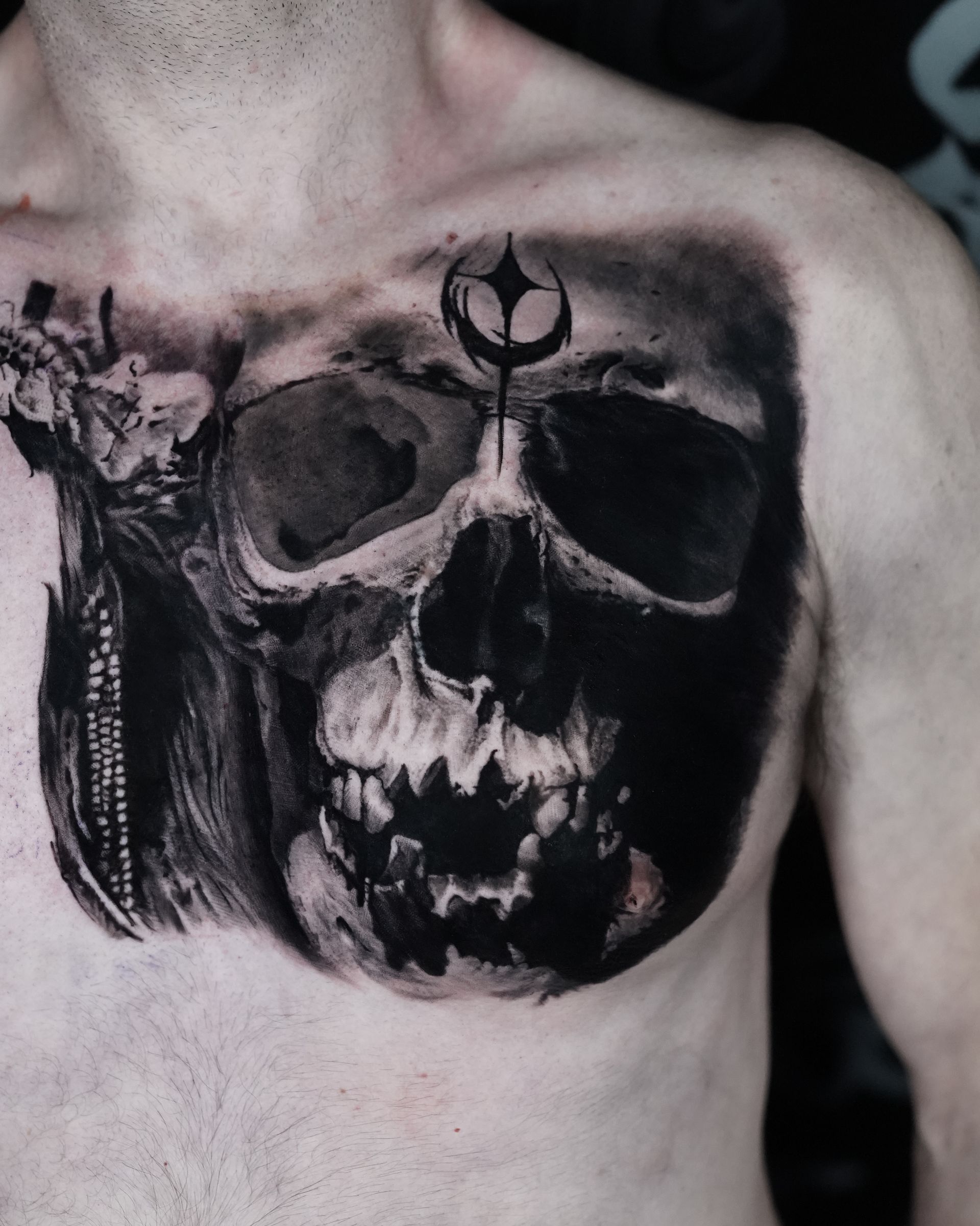 A man has a tattoo of a skull on his chest