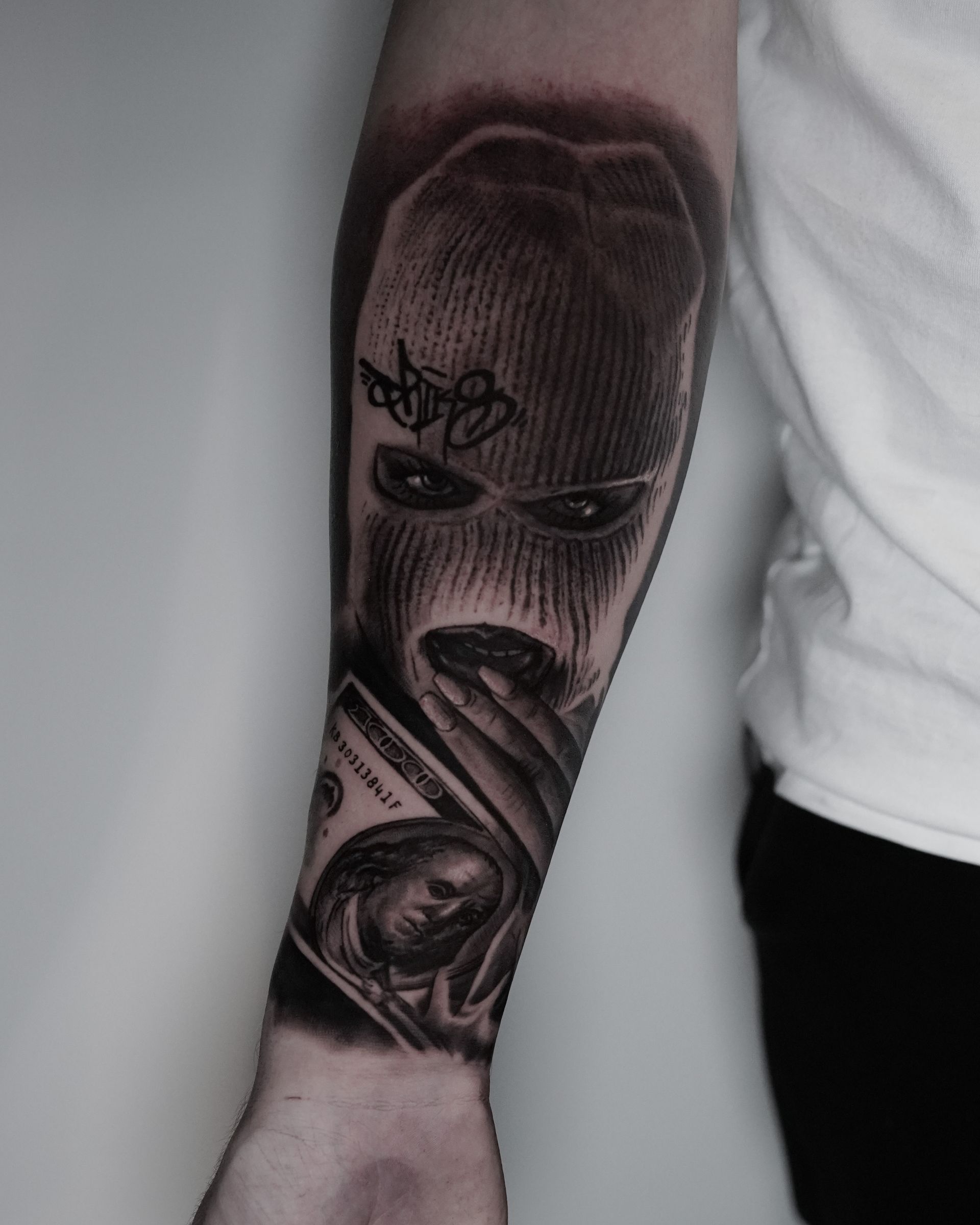 A man has a tattoo of a man in a ski mask holding a stack of money.