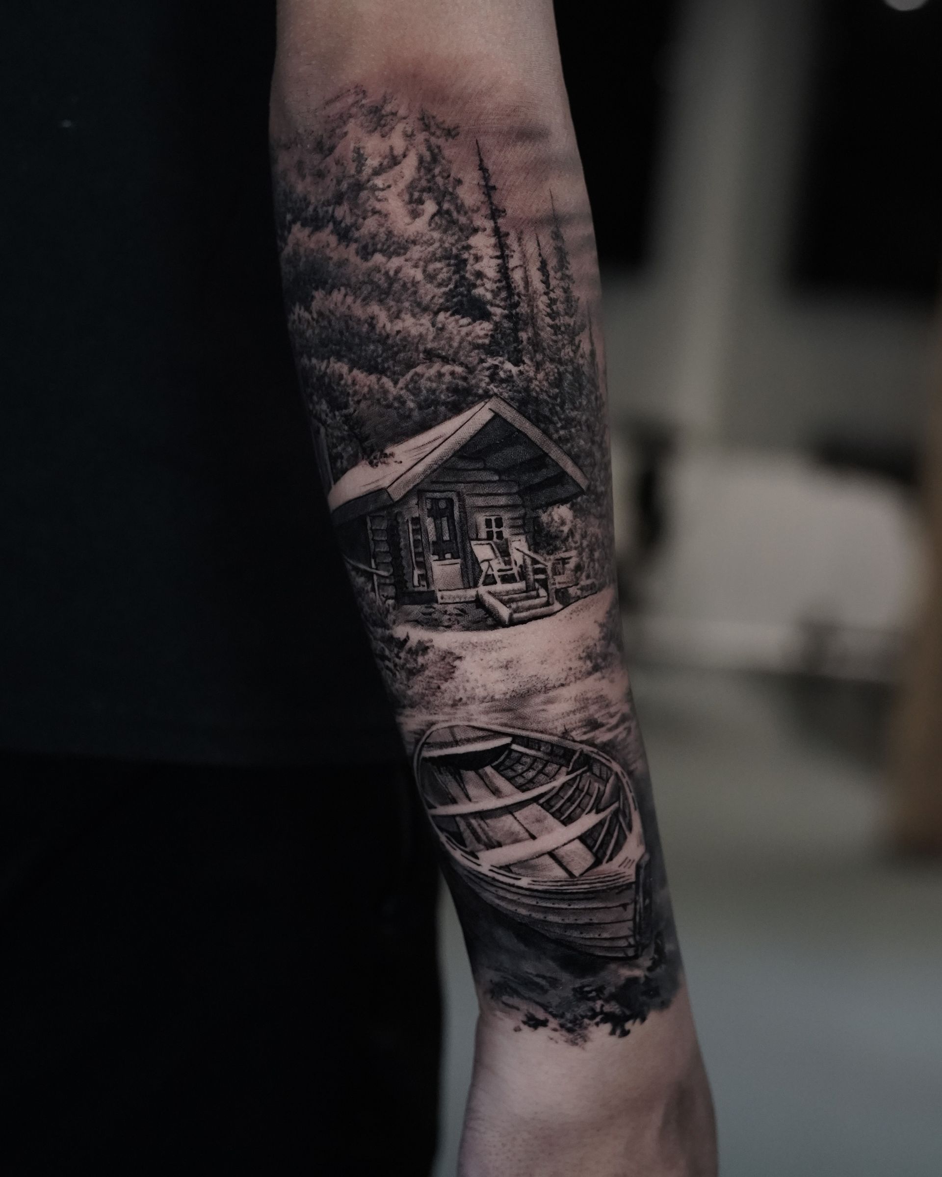 A person has a tattoo of a cabin and a boat on their forearm.