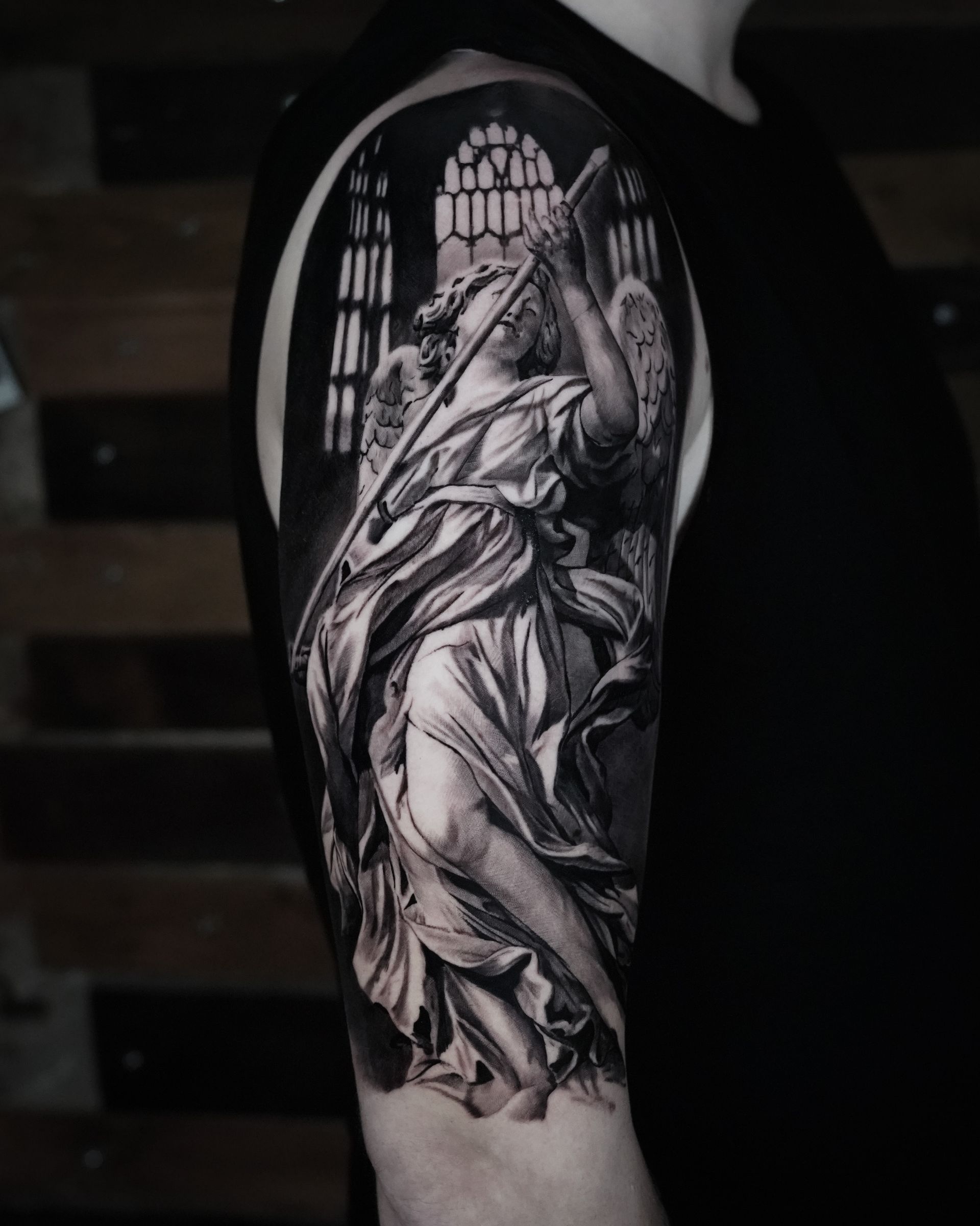 A black and white tattoo of an angel on a man 's arm.