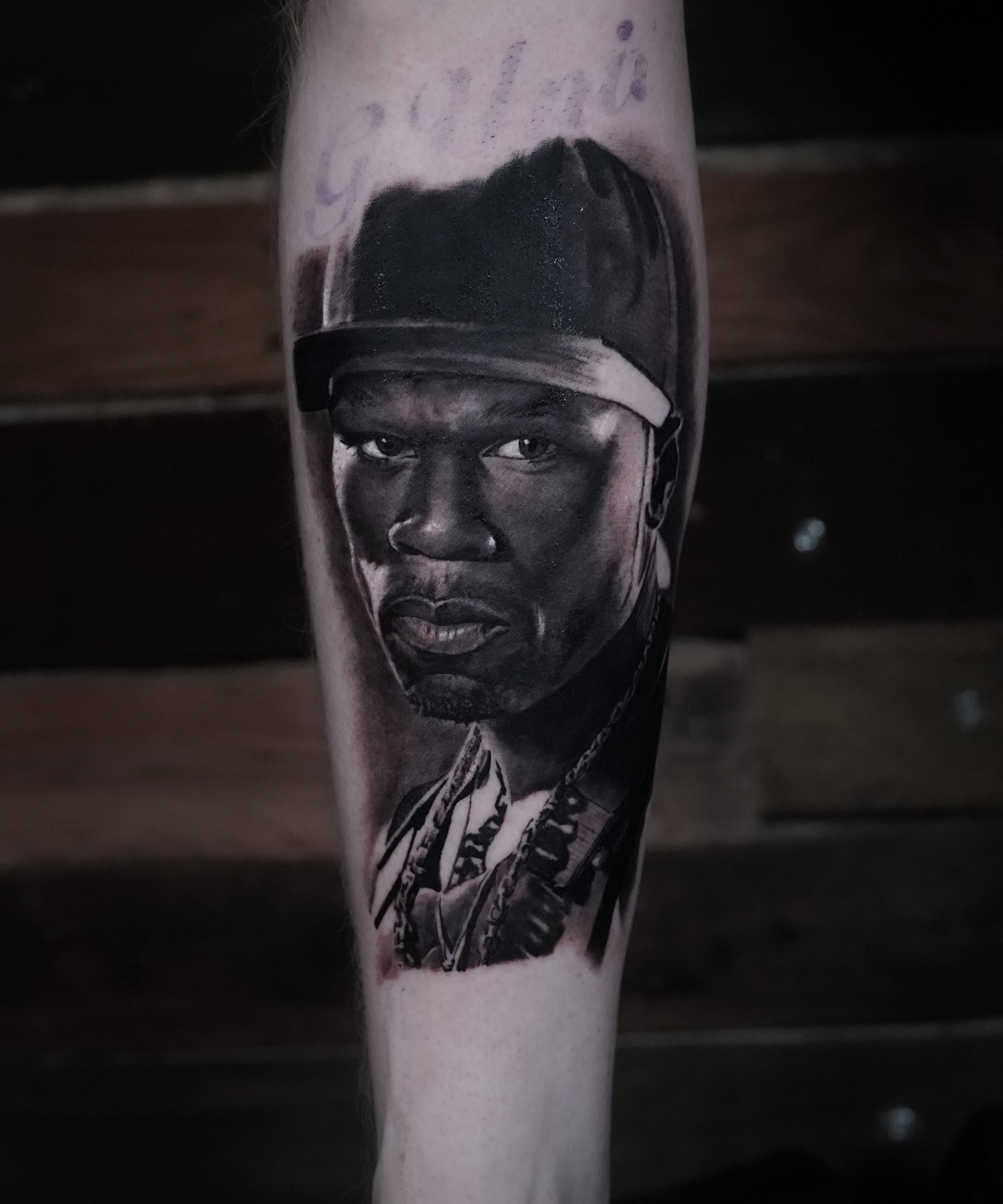 A black and white tattoo of a man in a baseball cap on a leg.