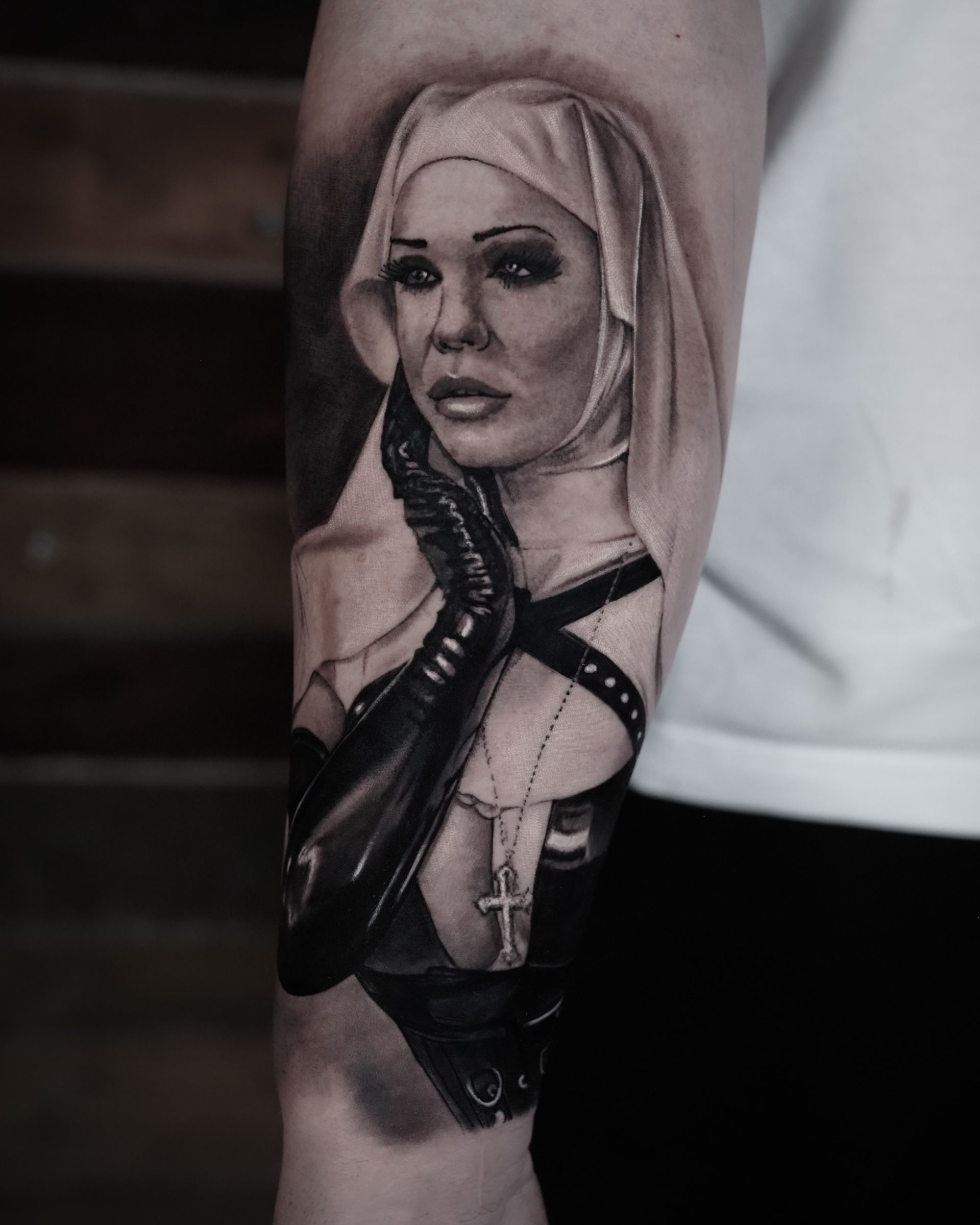 A man has a tattoo of a nun on his arm.