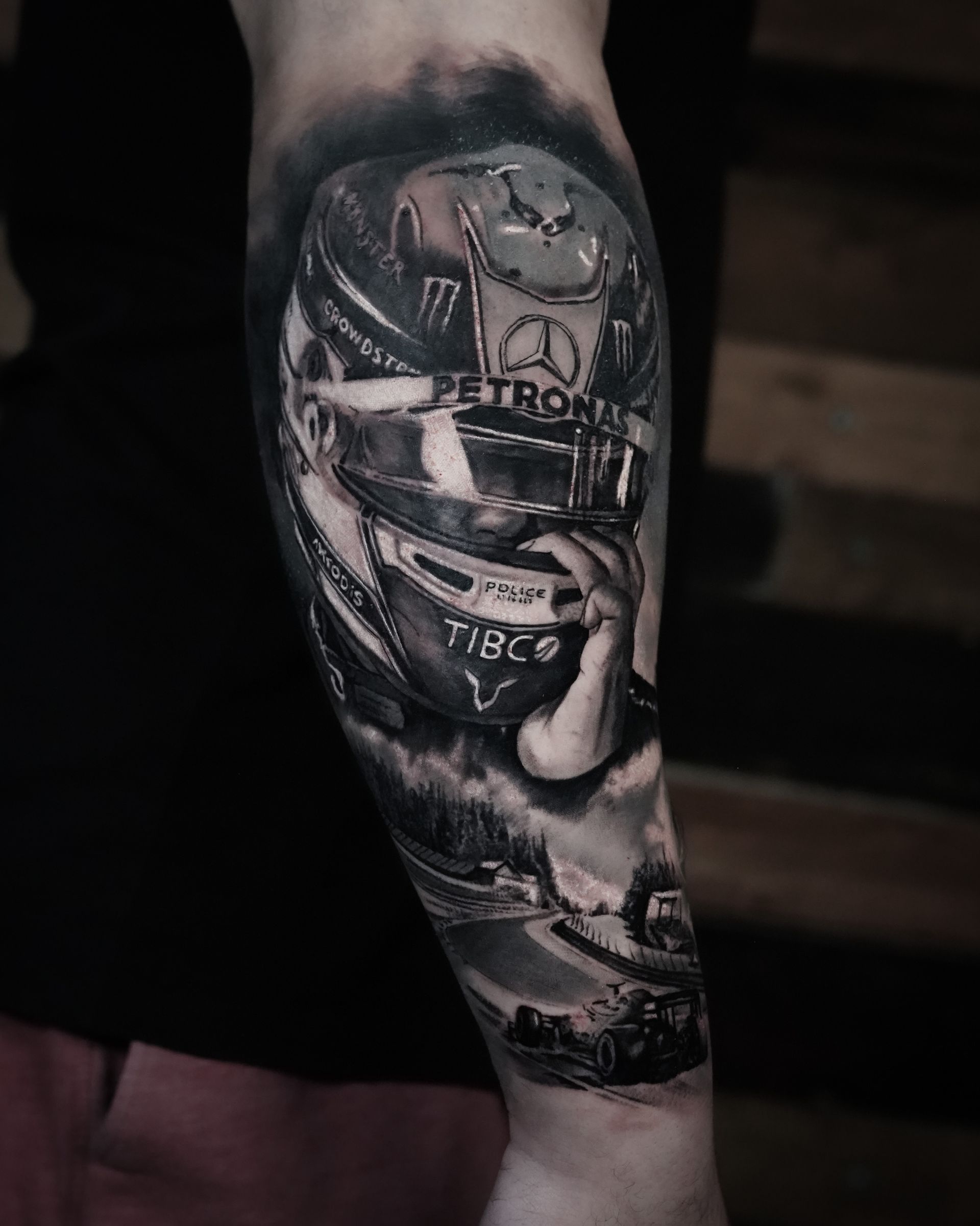 A black and white tattoo of a man wearing a helmet on his forearm.