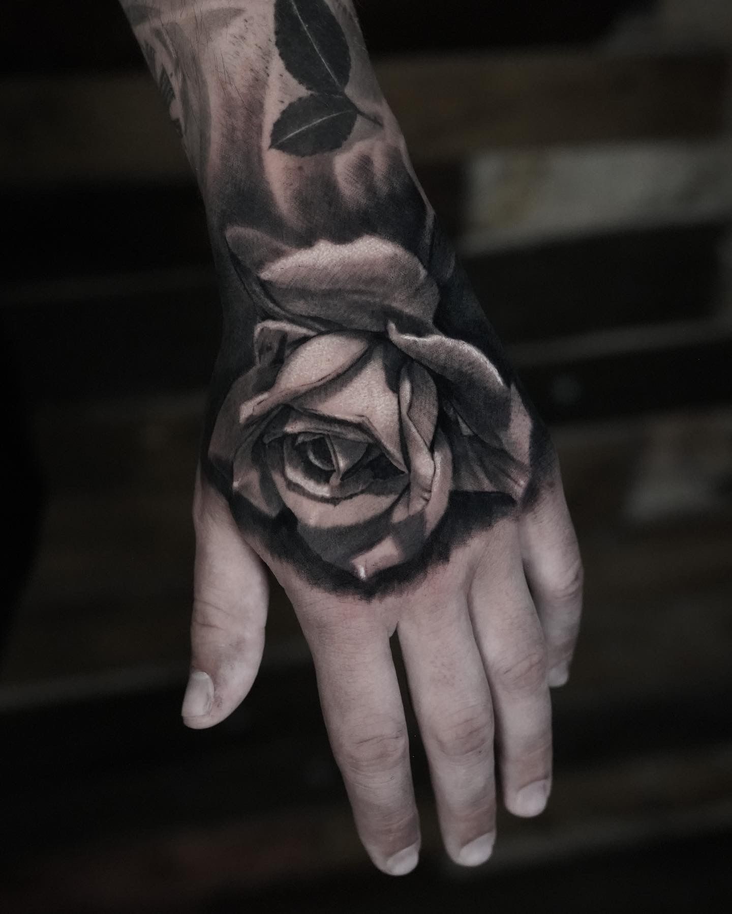 A person has a tattoo of a rose on their hand.